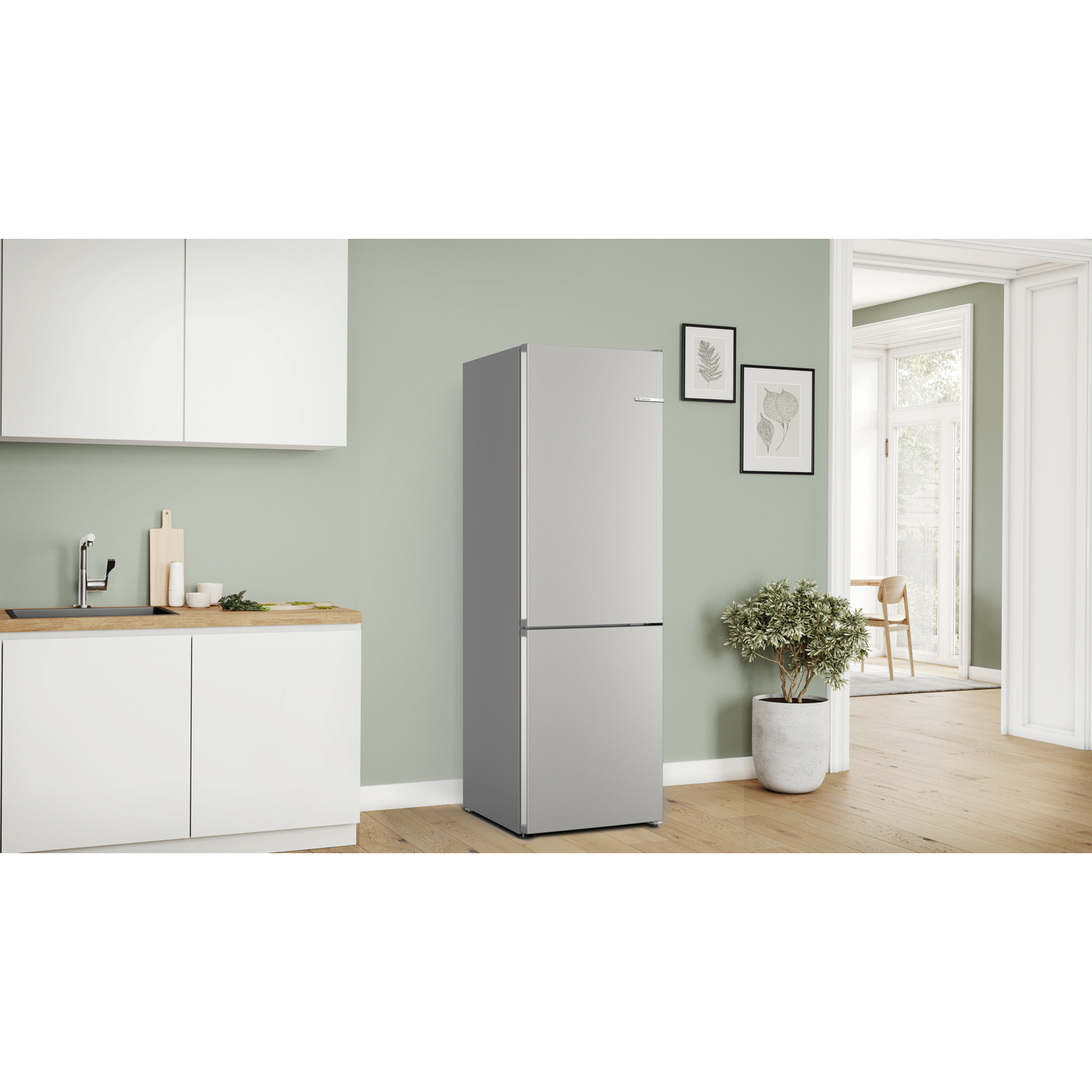 Een zilveren koelkast in een lichte keuken met witte kasten en een houten vloer.