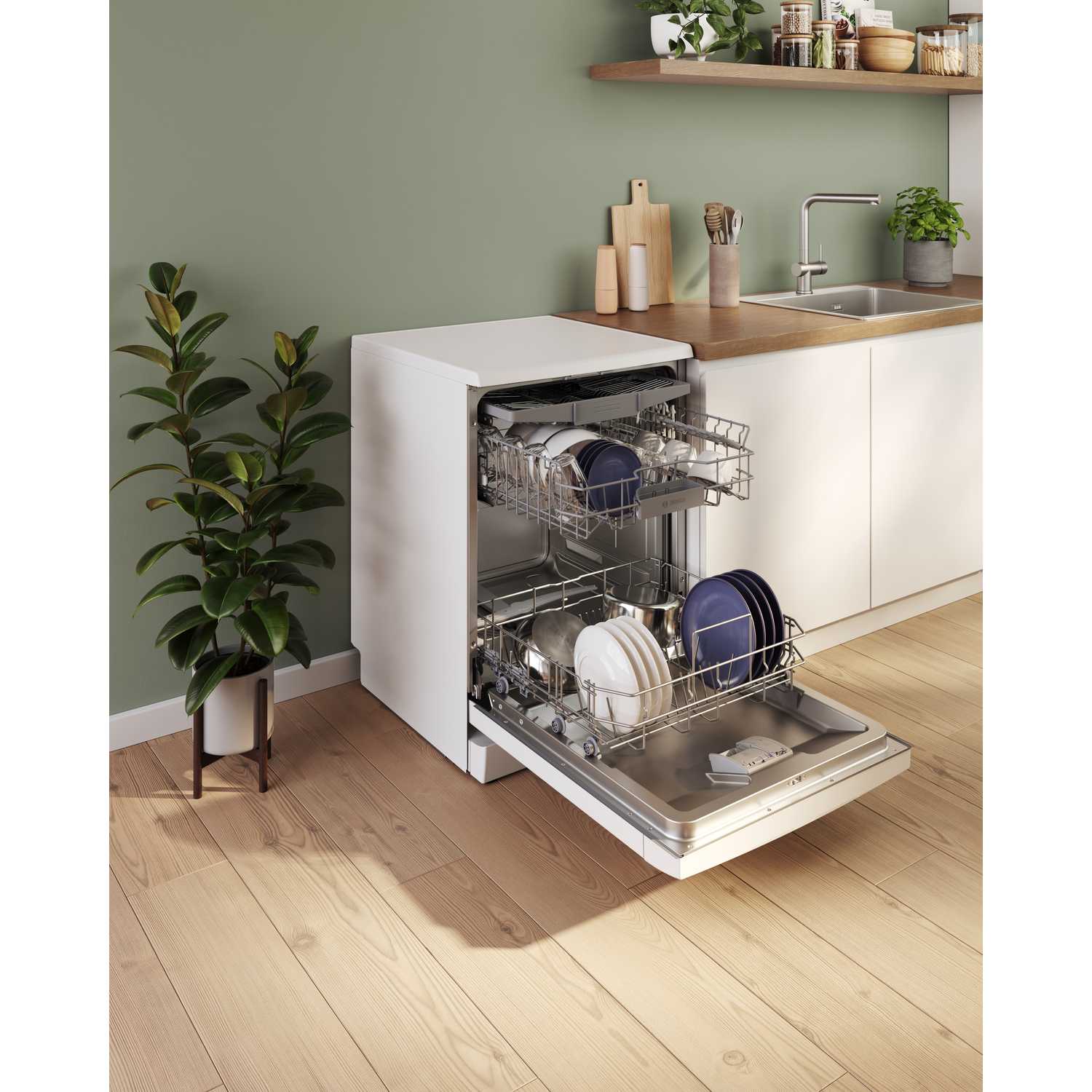 Witte vaatwasser open, gevuld met vaat, in een keuken met plant en gootsteen.