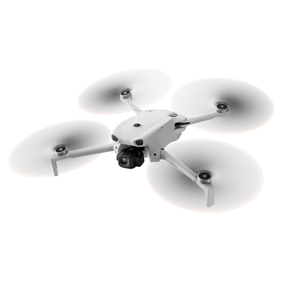 Kameralı beyaz bir dört pervaneli helikopter siyah arka planda uçuyor.
