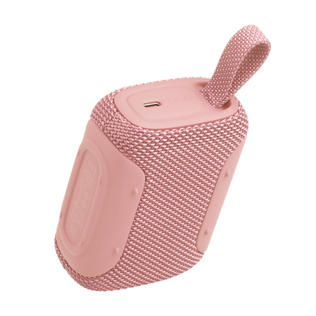Rózsaszín hordozható hangszóró szövetráccsal, USB-C porttal és hurokkal.