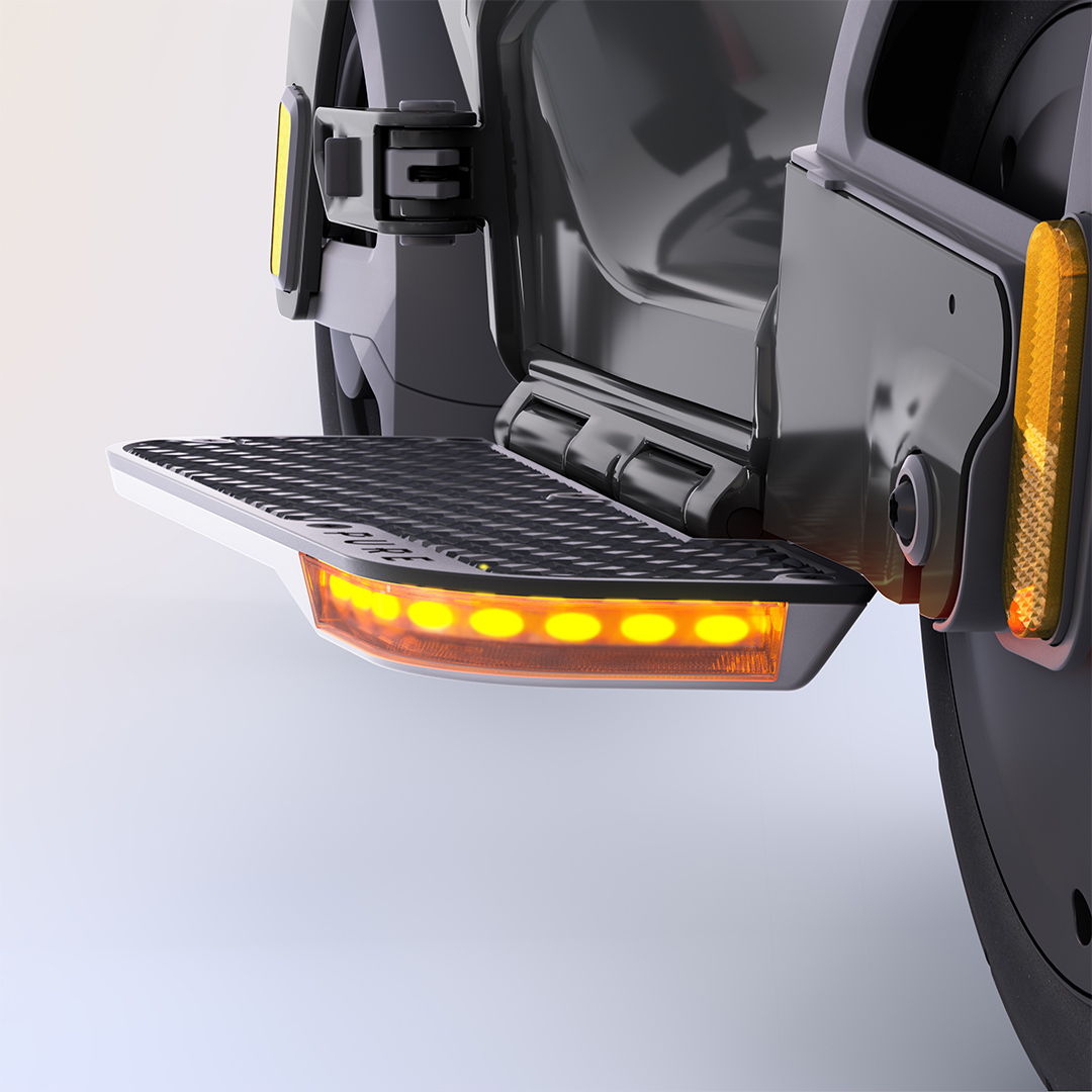 Ausklappbare Trittstufe mit gelben LEDs und Reflektoren an einem dunklen Fahrzeugteil.
