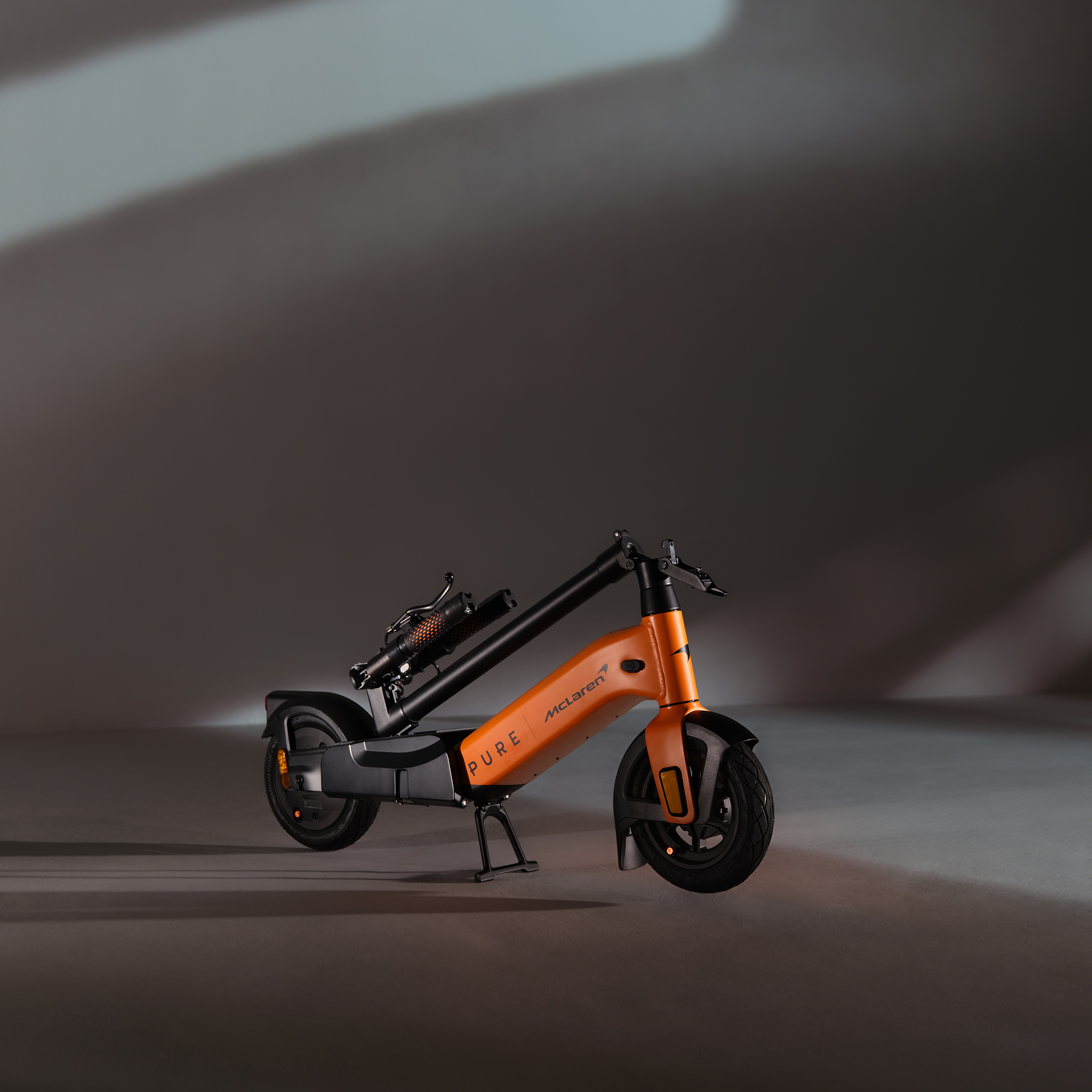 Ein orangefarber E-Scooter mit McLaren-Logo steht auf einem Ständer.