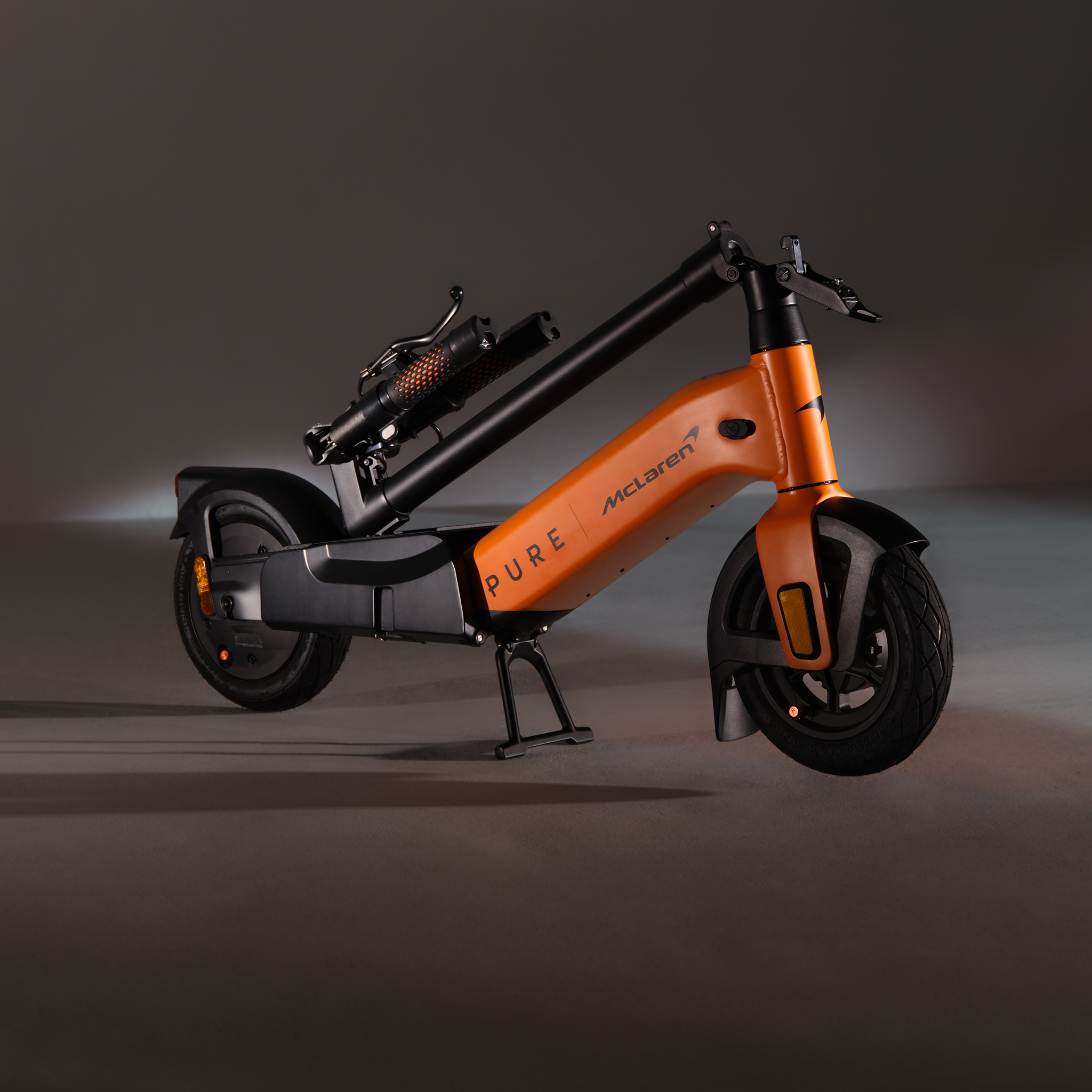 Ein orange-schwarzer Elektroroller der Marke McLaren steht auf einem Ständer.