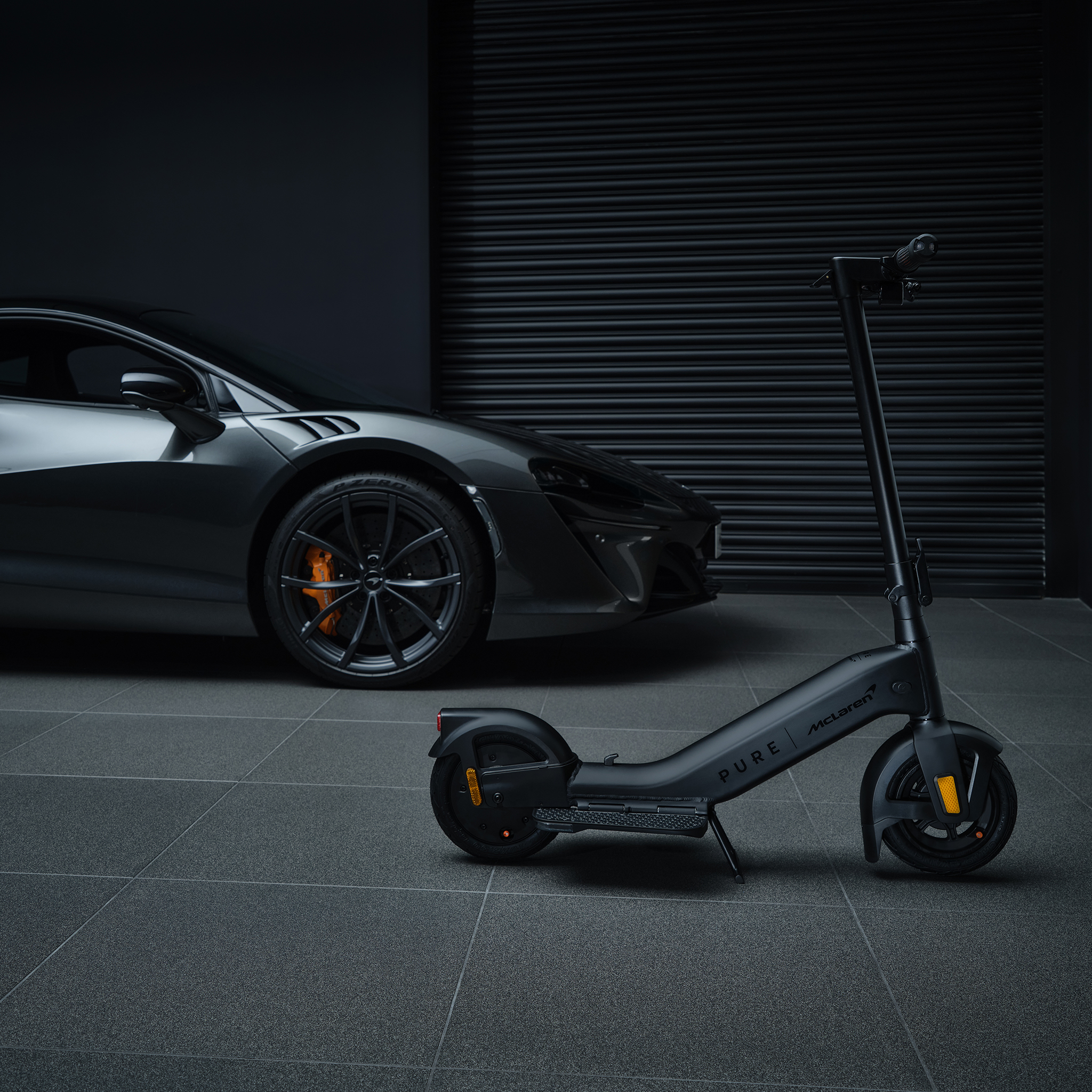 Ein schwarzer E-Scooter steht neben einem dunklen Sportwagen vor einem Rolltor.