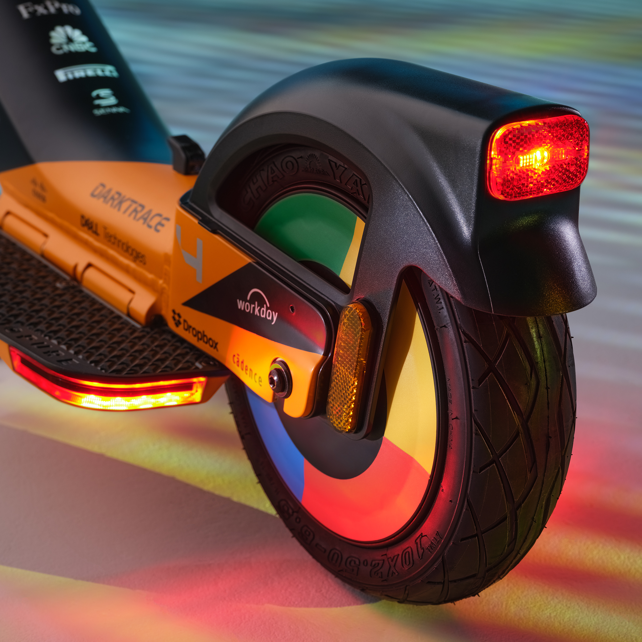 Orange E-Scooter mit roten Rückleuchten und bedruckten Logos. Nahaufnahme.