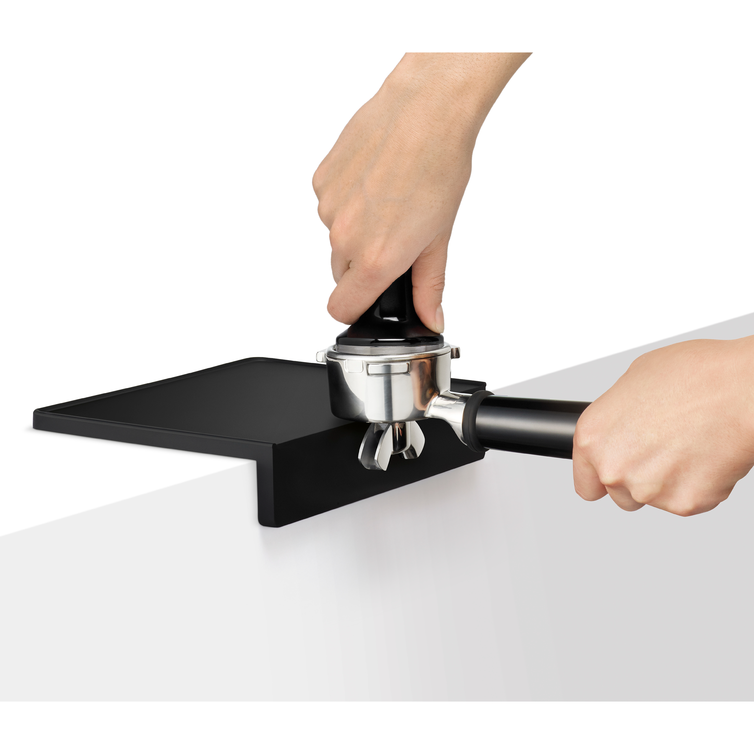 Eine Hand drückt einen Kaffeepressengriff auf eine schwarze Unterlage.