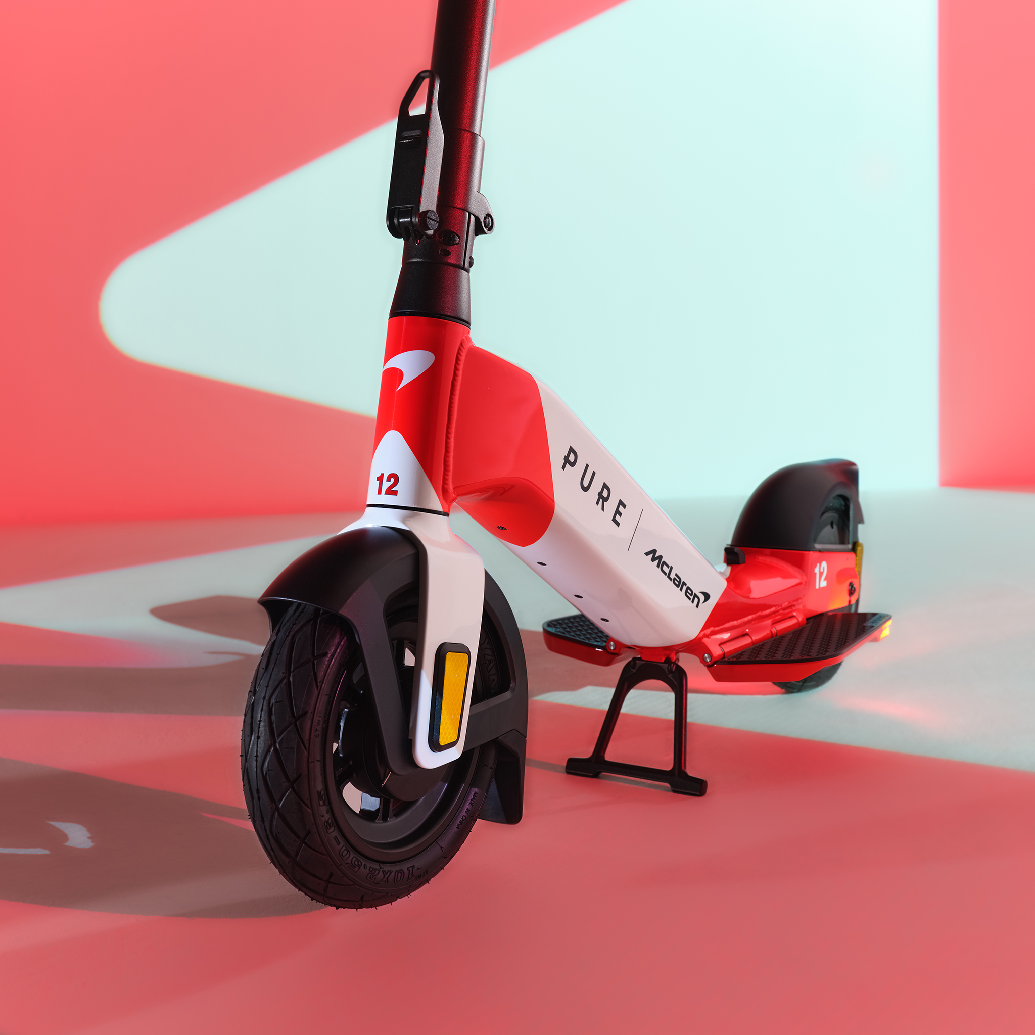 Ein roter und weißer E-Scooter mit der Nummer 12 steht auf einem Ständer.
