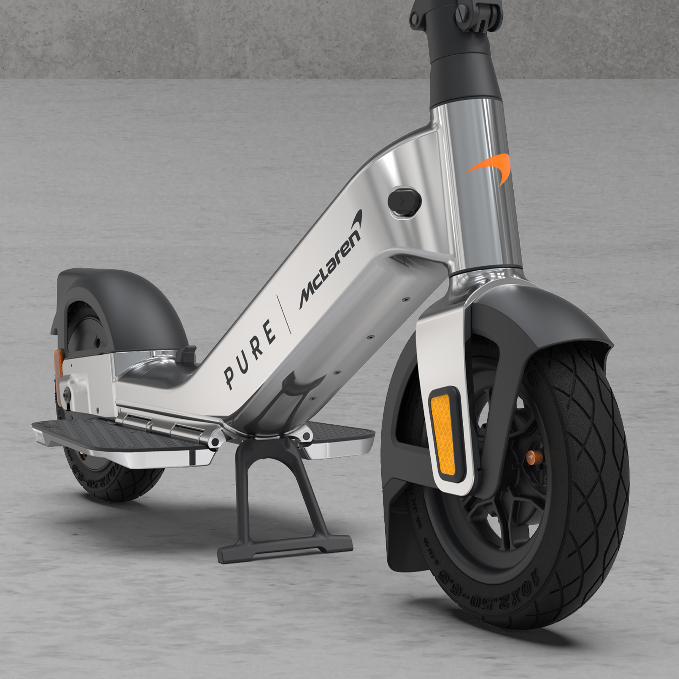 Ein silberner E-Scooter mit orangem McLaren-Logo und schwarzem Rad steht auf Beton.