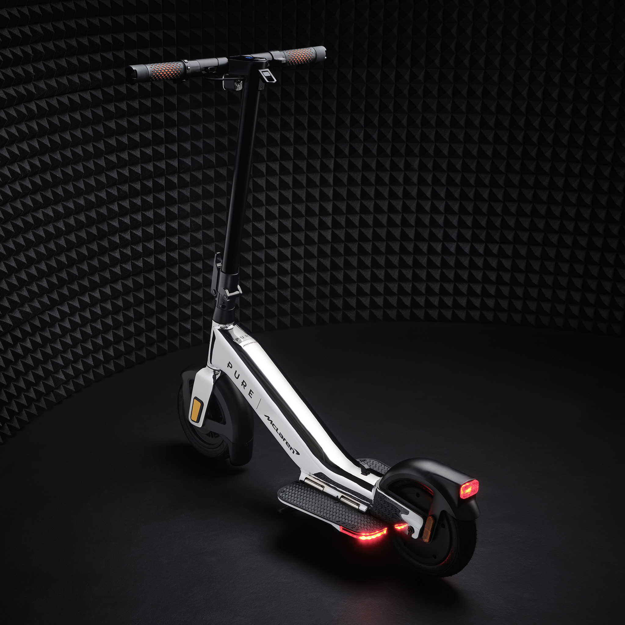 Weißer McLaren Elektroroller mit schwarzen Akzenten, beleuchtete rote Rücklichter.