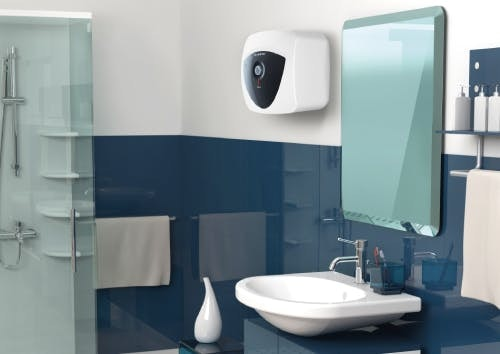Baño moderno con lavabo blanco, azulejos azules, ducha, espejo y calentador de agua.