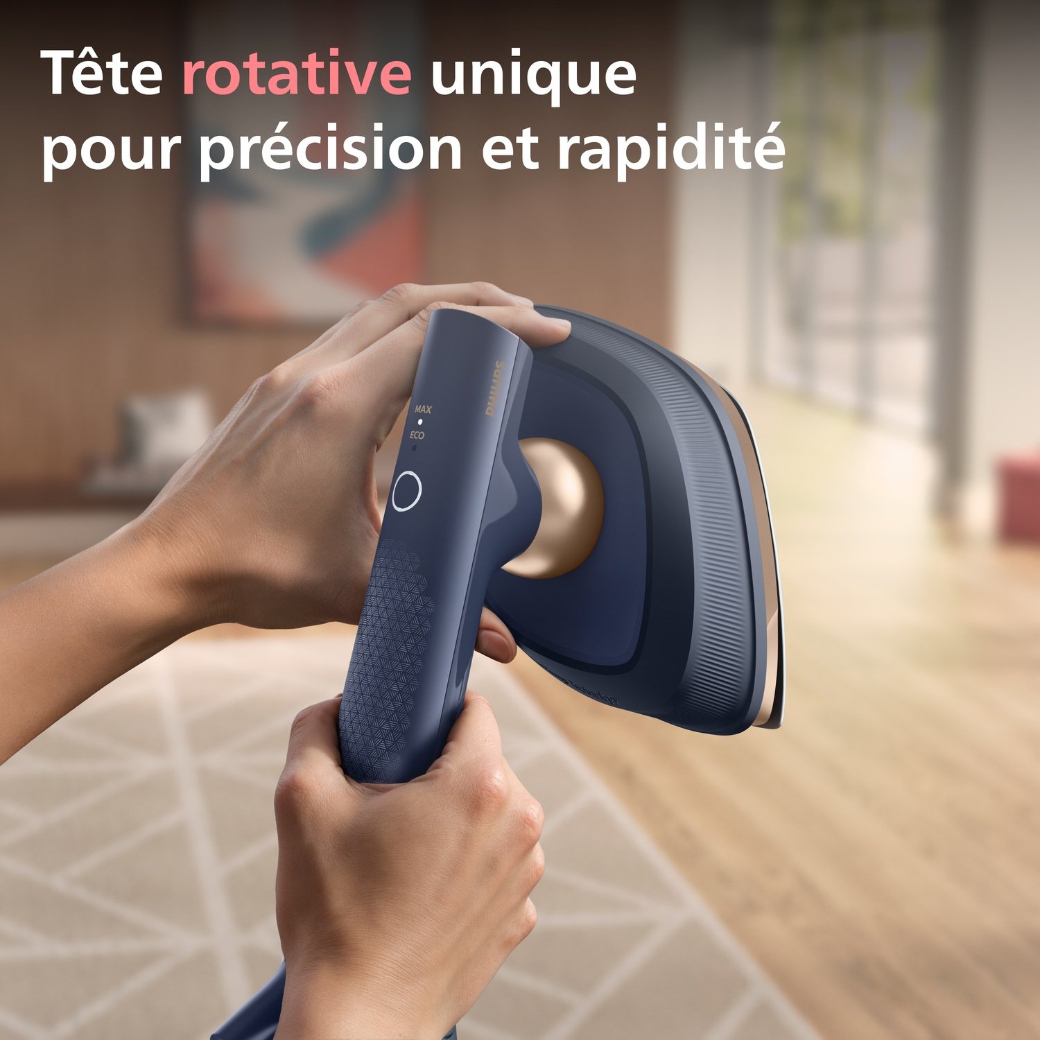Des mains tiennent un fer à repasser bleu foncé avec des accents dorés. L'arrière-plan est flou.