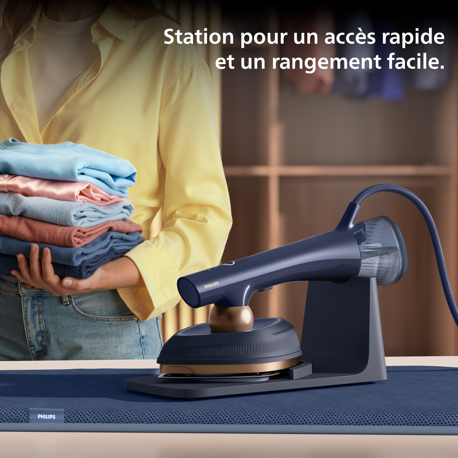 Une personne tient une pile de vêtements à côté d'un fer à vapeur sur son socle.
