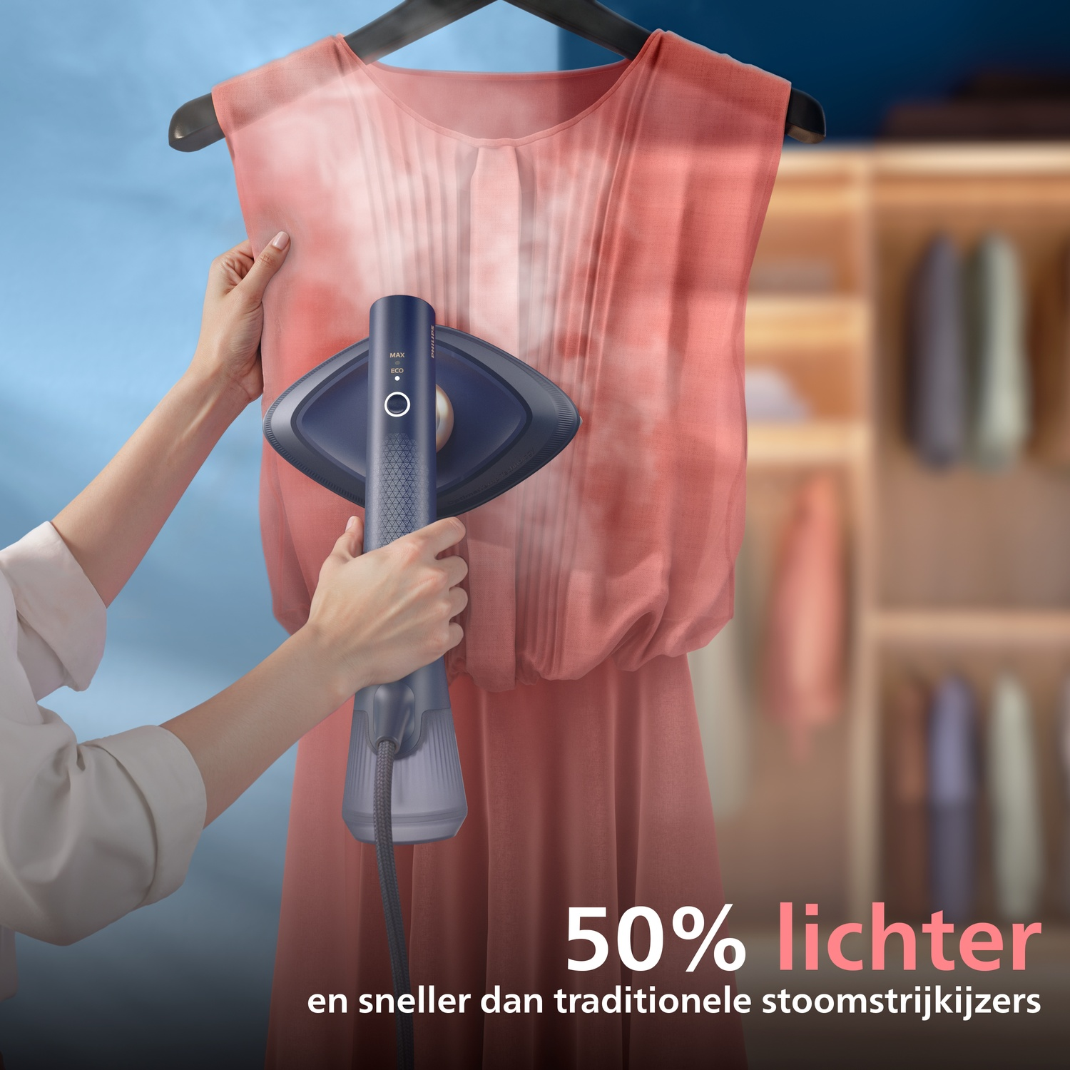 A hand holds a garment steamer, steaming a pink dress hanging in a closet.