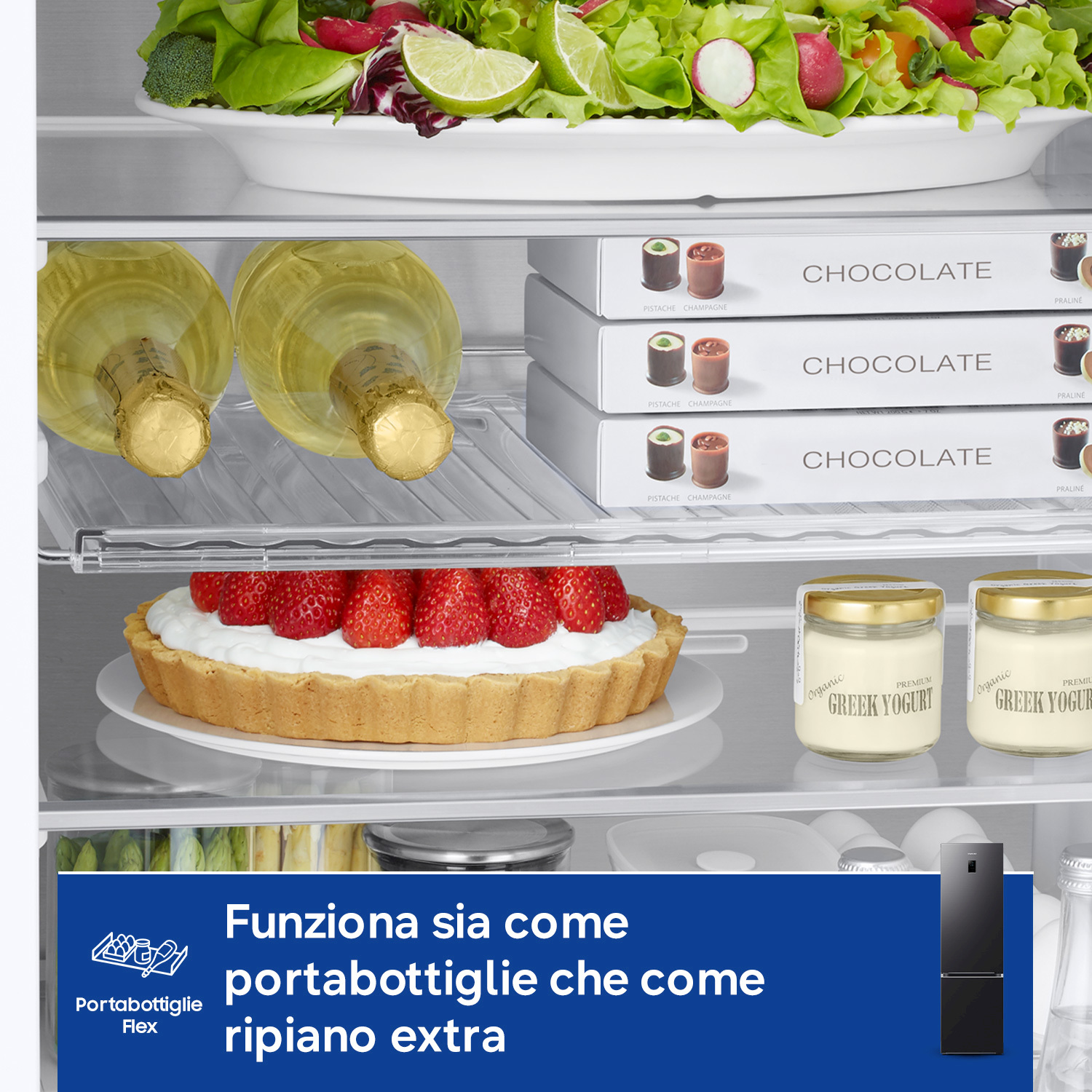Interno frigorifero con insalata, champagne, cioccolatini, crostata di fragole, yogurt e un frigo nero.