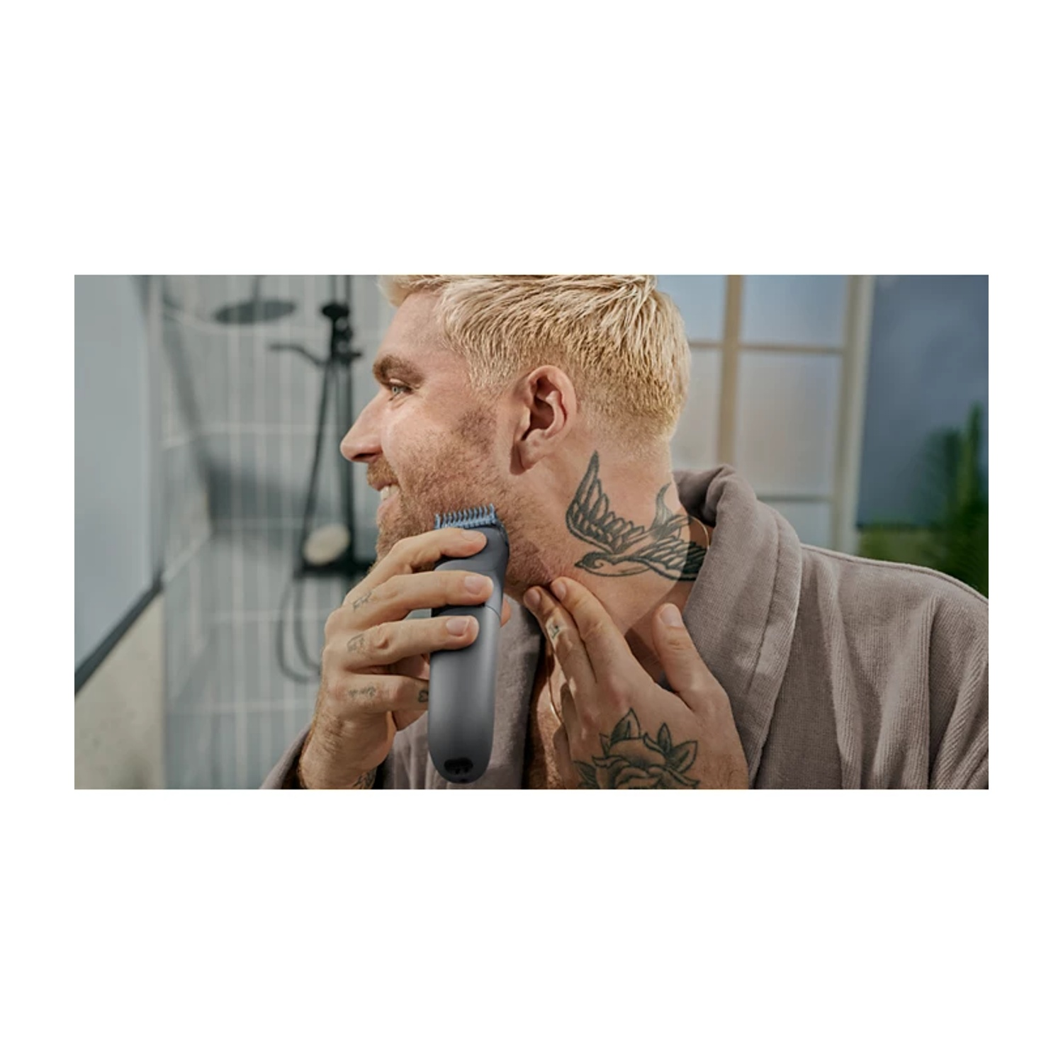 Un uomo con capelli biondi e tatuaggi si rade il collo con un trimmer scuro.
