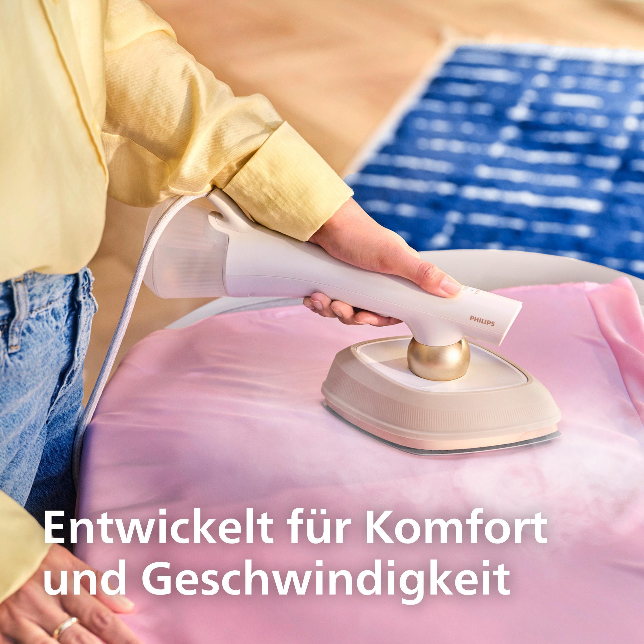 Eine Hand benutzt einen Dampfbügler auf einem rosa Stoff. Rauch steigt auf.