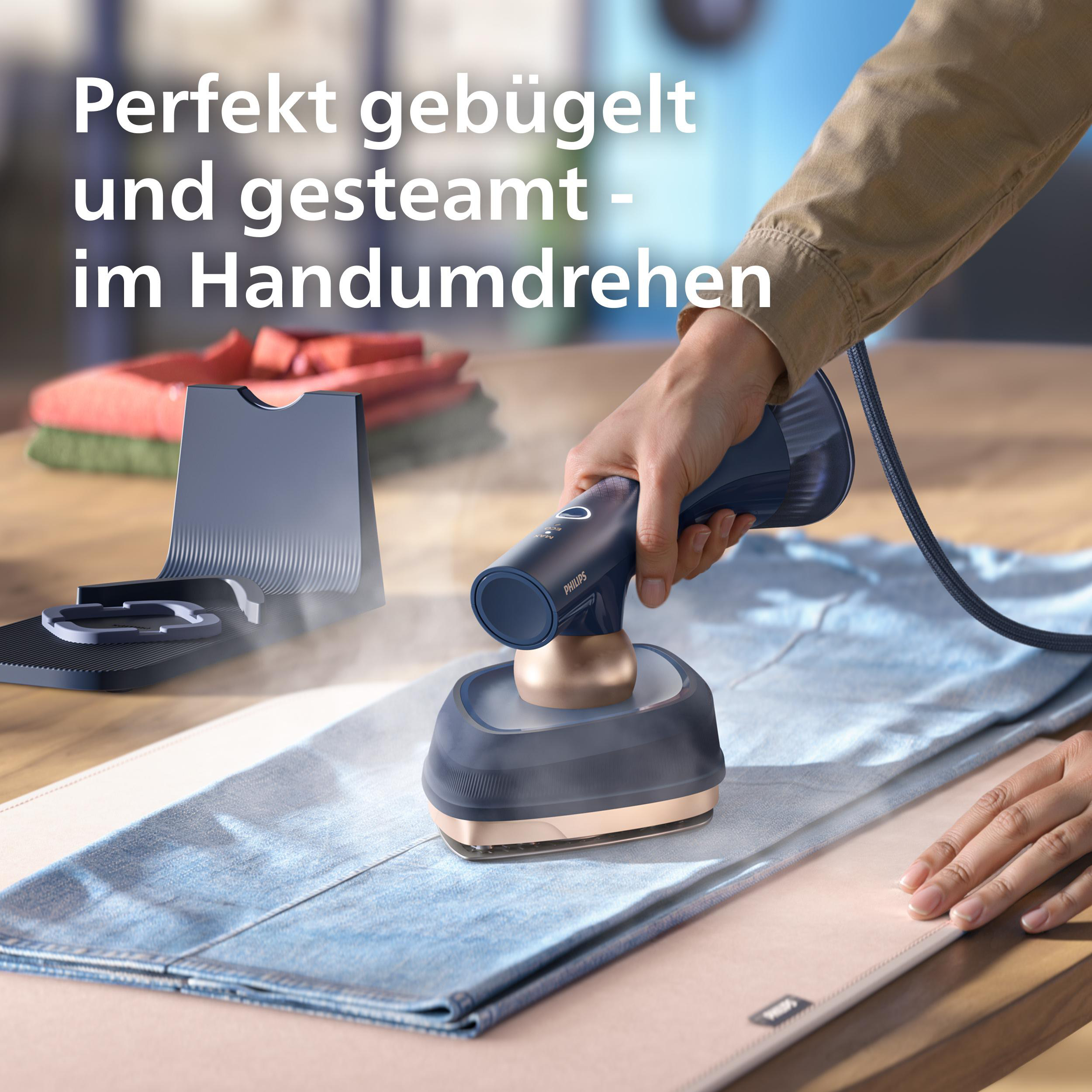 Handheld-Dampfglätter glättet blaue Jeans mit Dampf. Ein Ständer ist daneben.
