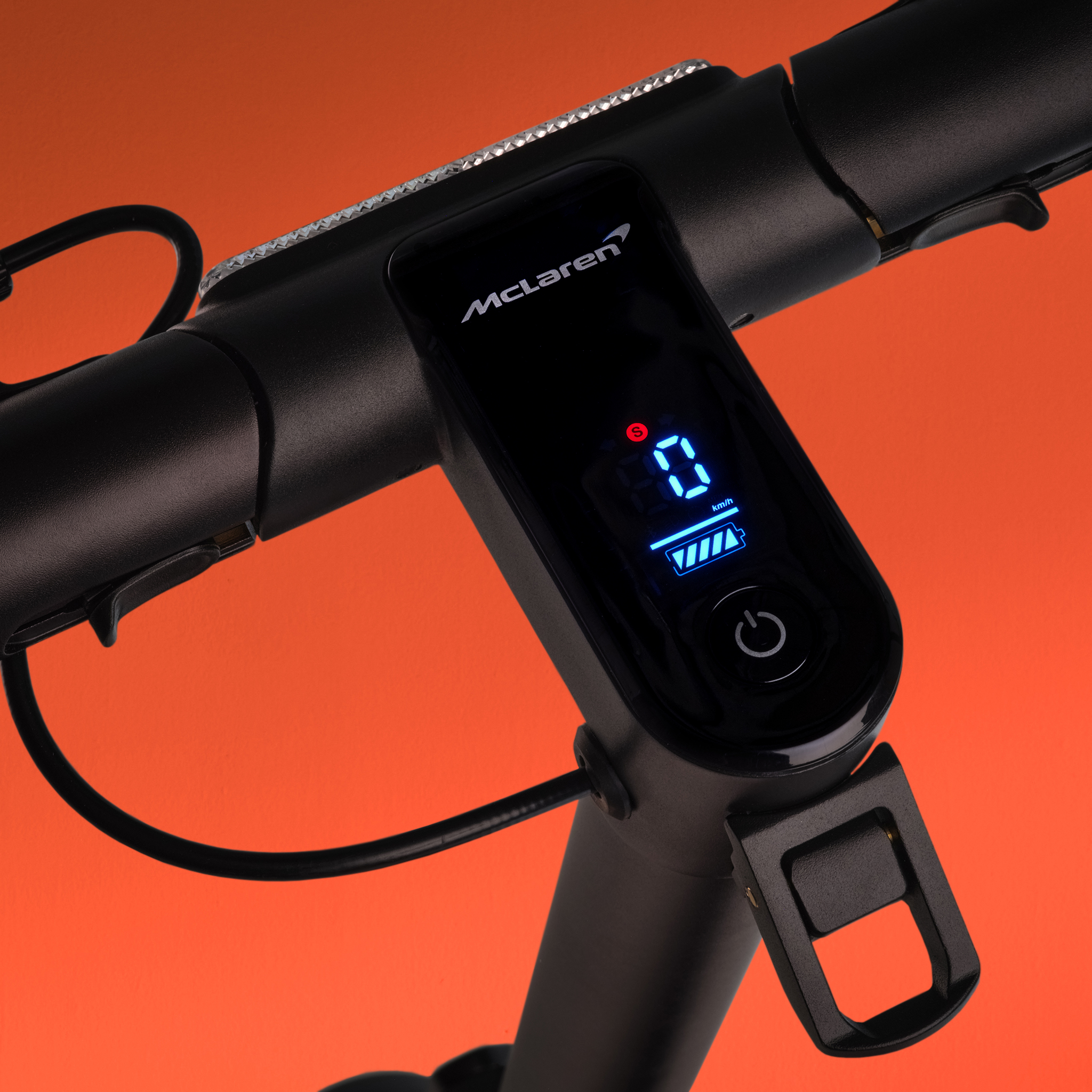 Nahaufnahme des Lenkers eines E-Scooters mit McLaren-Logo und digitaler Anzeige.