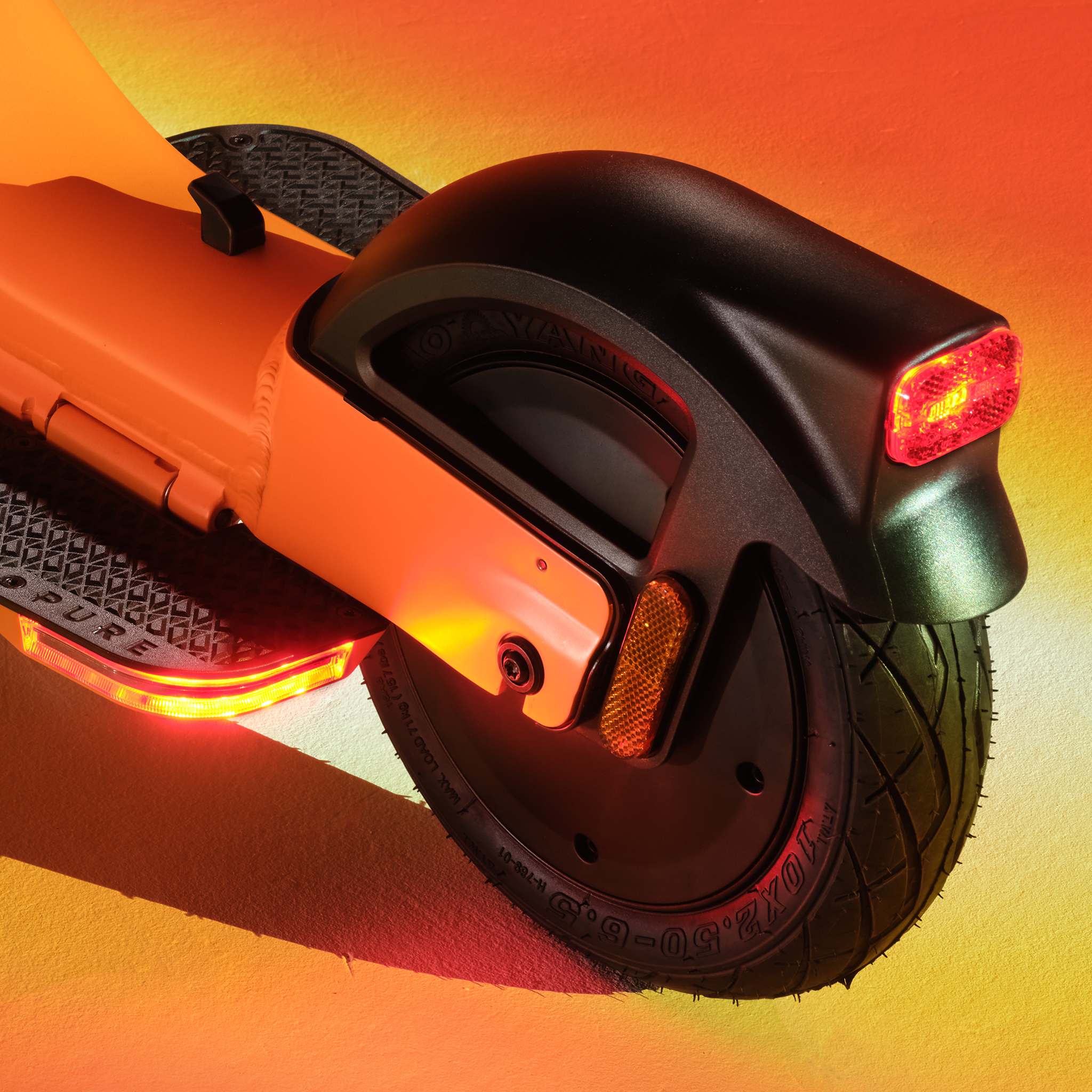 Nahaufnahme eines orangen Elektrorollers mit Rücklicht und Rad.