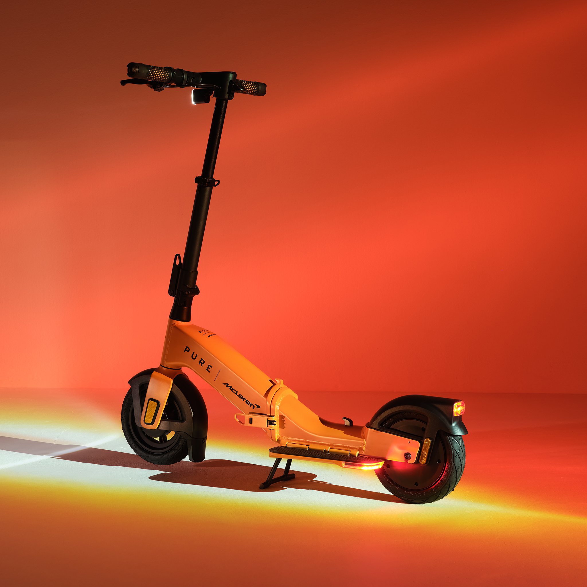 Ein gelber E-Scooter mit schwarzem Lenker und Rädern steht auf einem orangefarbenen Hintergrund.