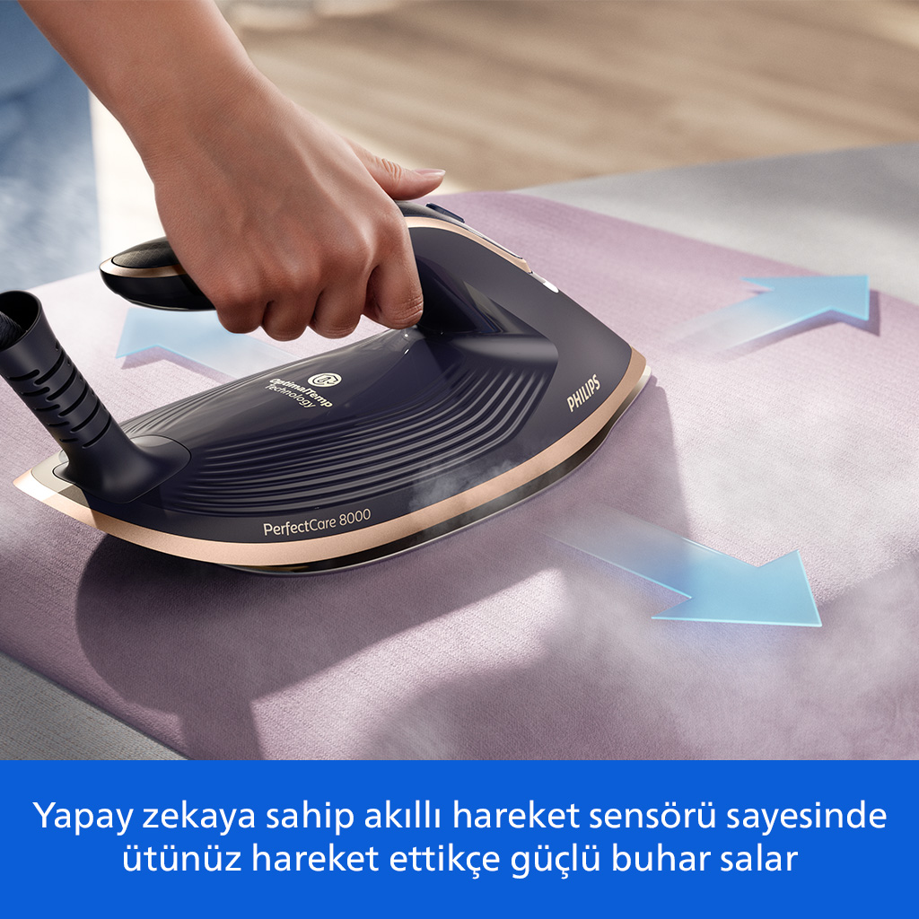 Bir el, mor kumaş üzerinde altın rengi vurgulara sahip lacivert bir ütü tutuyor.