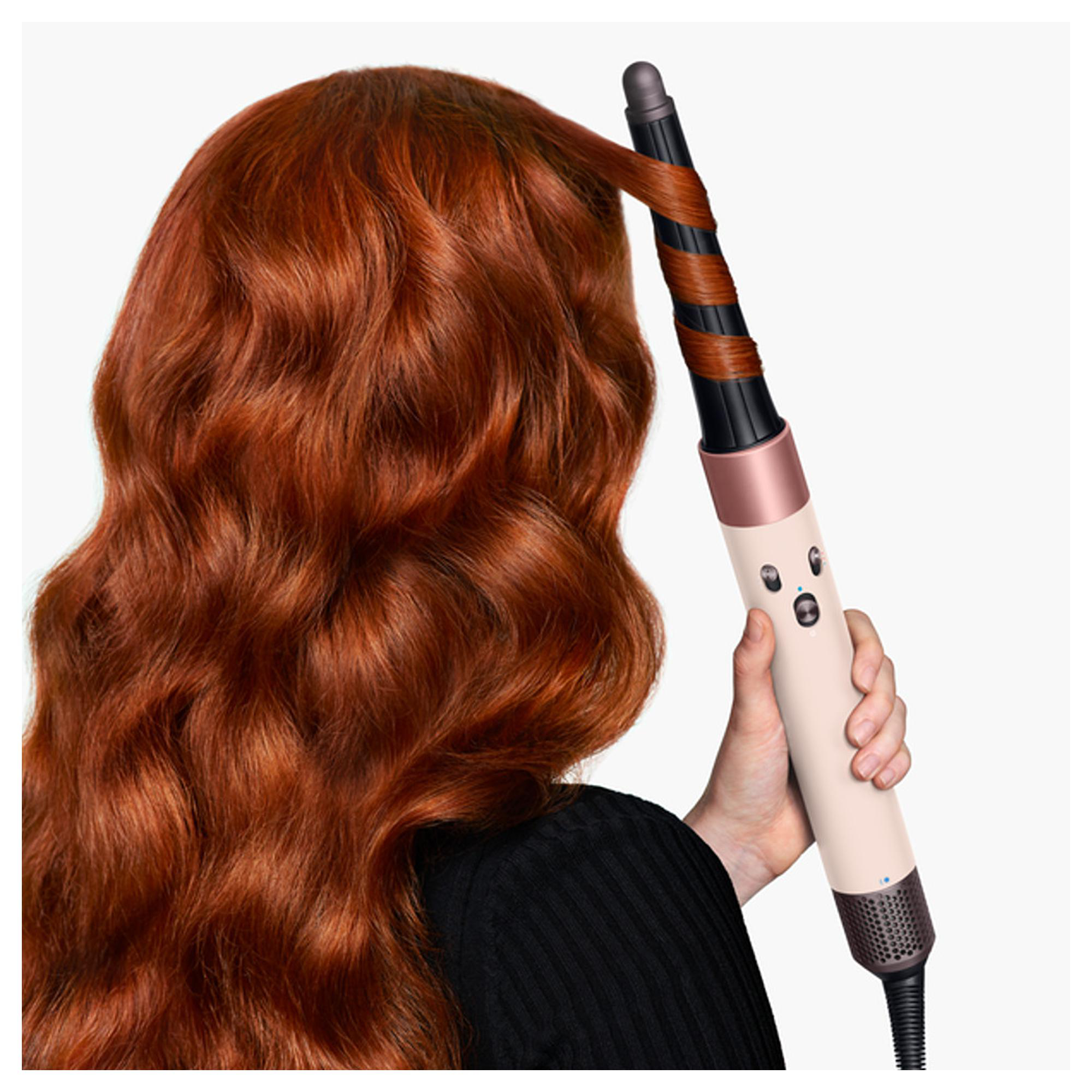 Eine Person mit langen, roten Haaren benutzt einen Lockenstab, um die Haare zu stylen.