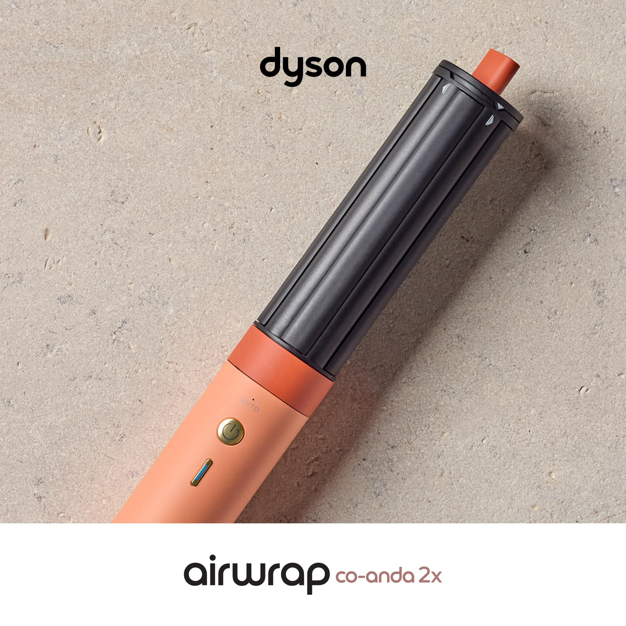 Ein korallenfarbener Dyson Airwrap mit schwarzem Aufsatz auf hellem Stein.