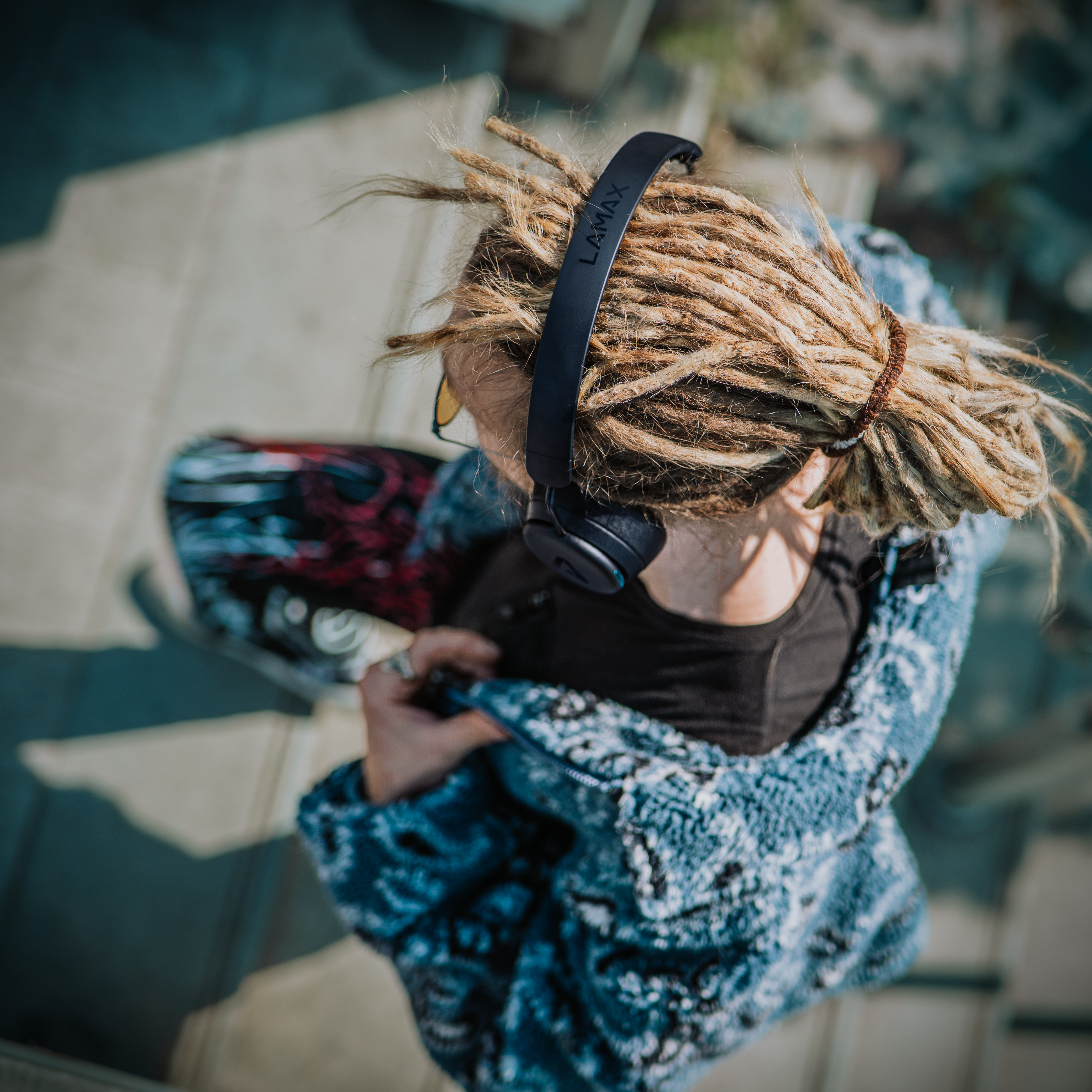 Dreadlockos, fejhallgatós személy gördeszkán.