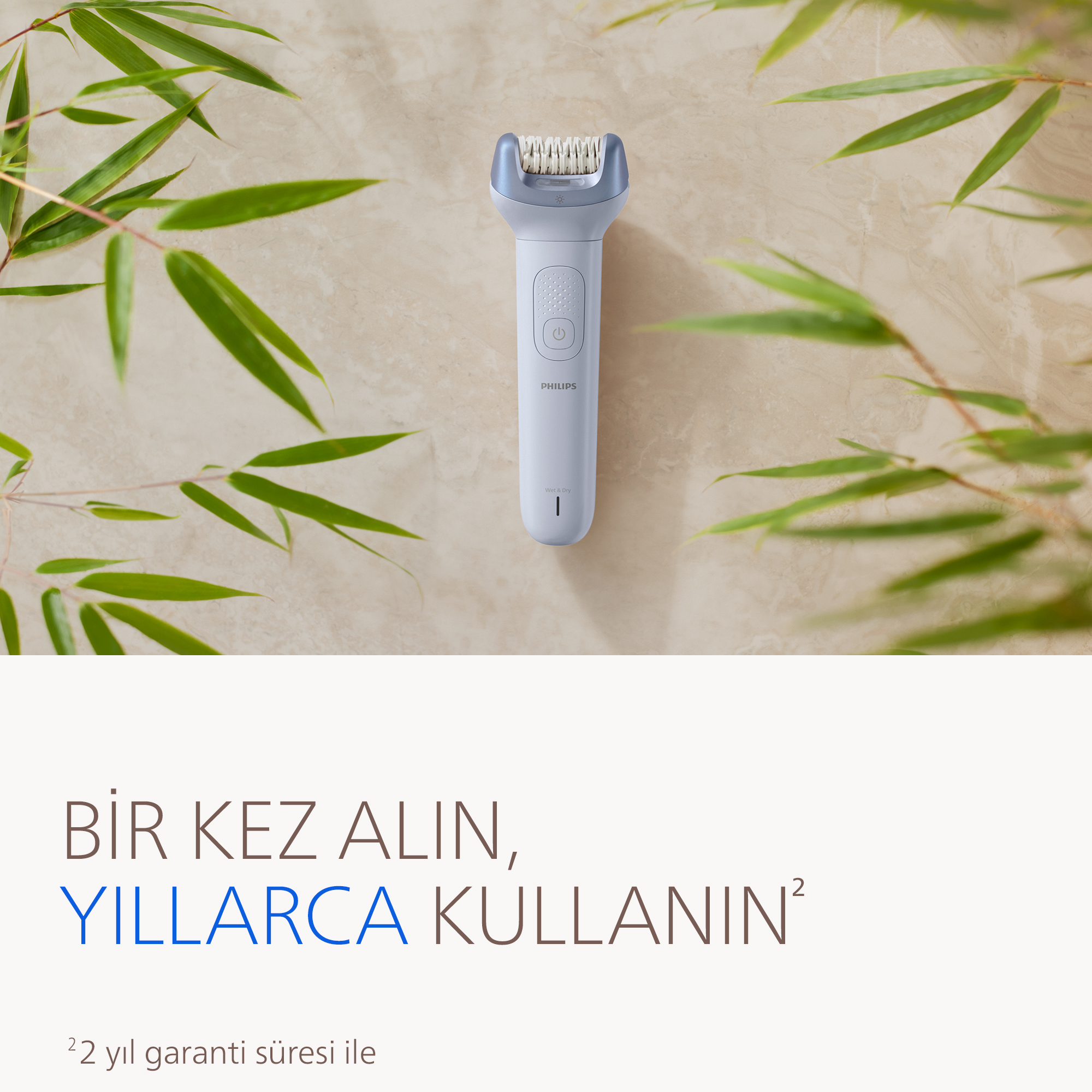 Arkada bambu yaprakları olan beyaz bir Philips epilatör.
