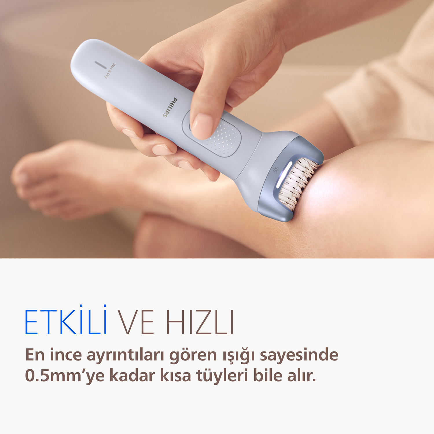 Bir el, Philips epilatörü bir bacağa tutuyor.