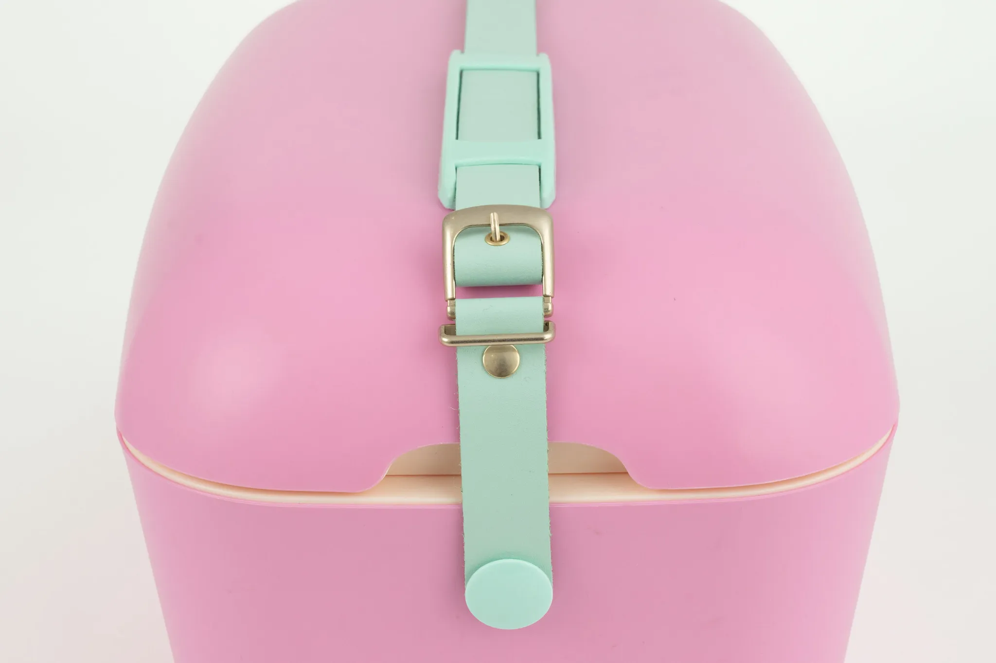 Una custodia rosa chiaro con cinturino verde menta e fibbia argentata.