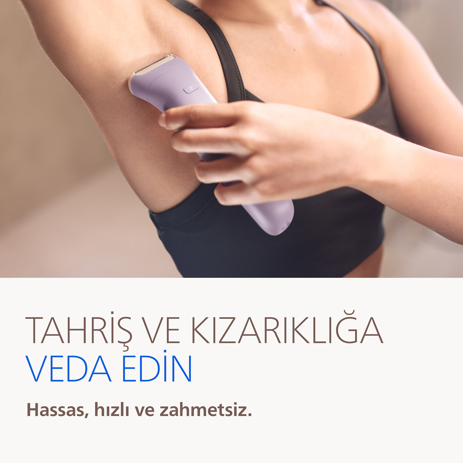 Kadın, koltuk altını lavanta rengi epilatör ile tıraş ediyor.