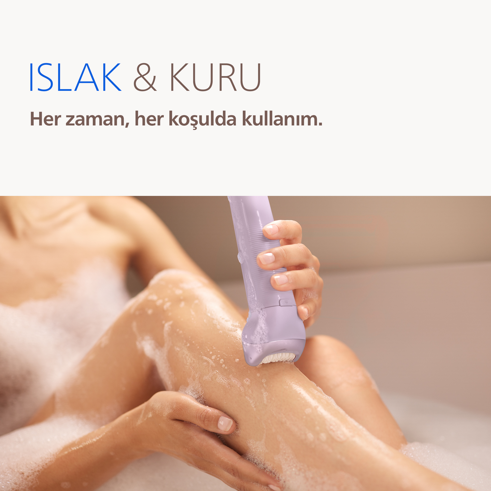 Bir el, köpüklü banyodaki kadının bacağında mor renkli epilatör kullanıyor.