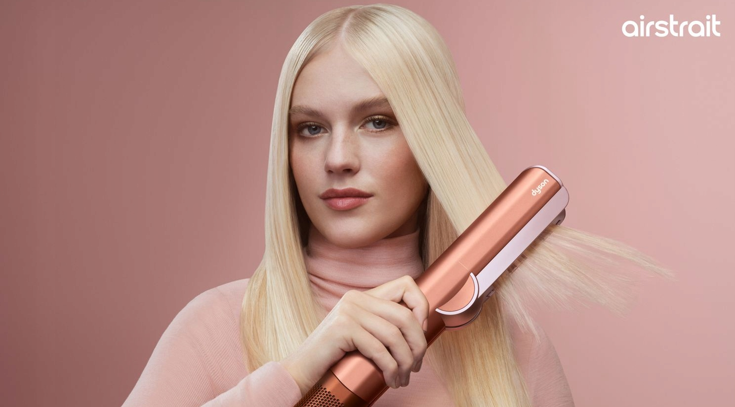 Kobieta z blond włosami prostuje włosy za pomocą różowozłotej prostownicy.