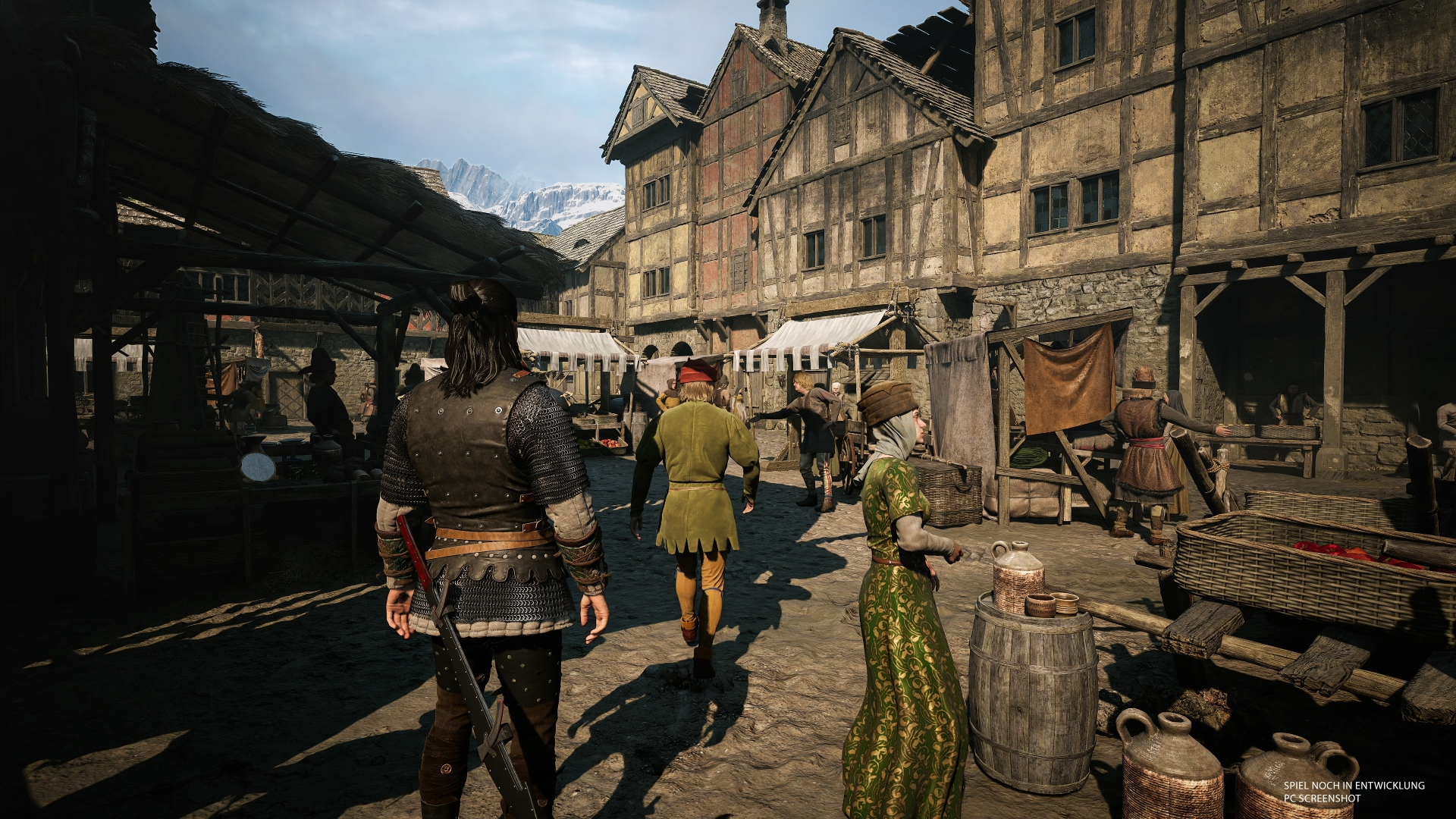 Mittelalterlicher Markt mit Menschen in Kleidung der Epoche, Fachwerkhäusern und Bergen im Hintergrund.