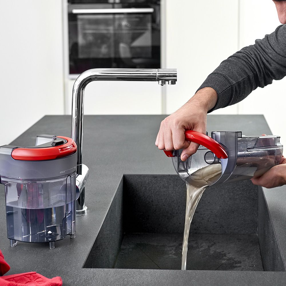 Una persona vacía un cubo de suciedad con agua sucia en un fregadero junto a un grifo.