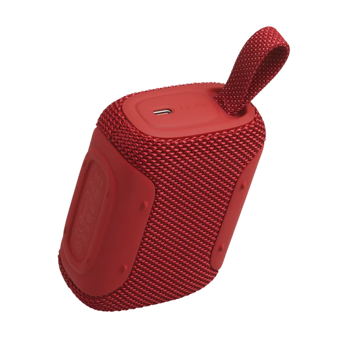 Altavoz Bluetooth rojo de tela con asa, sobre fondo negro.