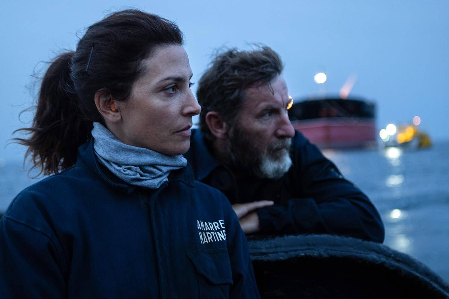 Eine Frau mit Zopf und ein Mann mit Bart auf einem Boot bei Dämmerung.