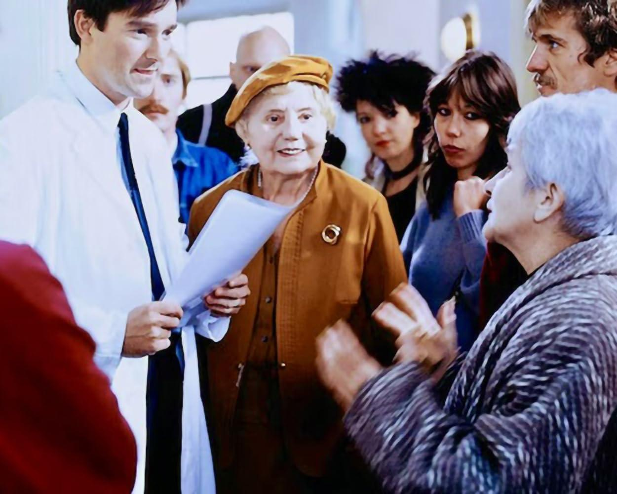 Eine Gruppe von Menschen steht zusammen, einige reden, eine Frau hält ein Dokument.