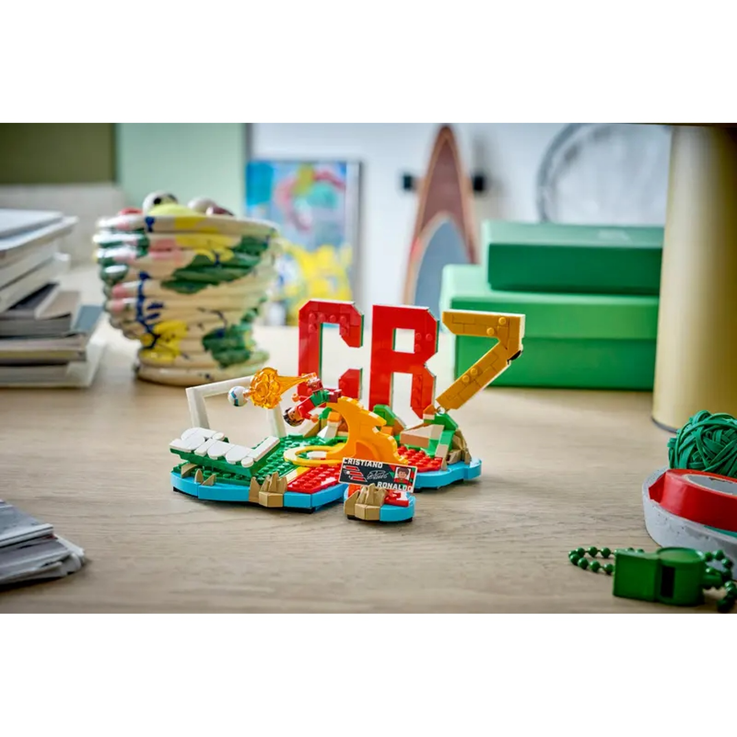 A Lego football set featuring the CR7 logo, a goal, and player figures on a wooden table.