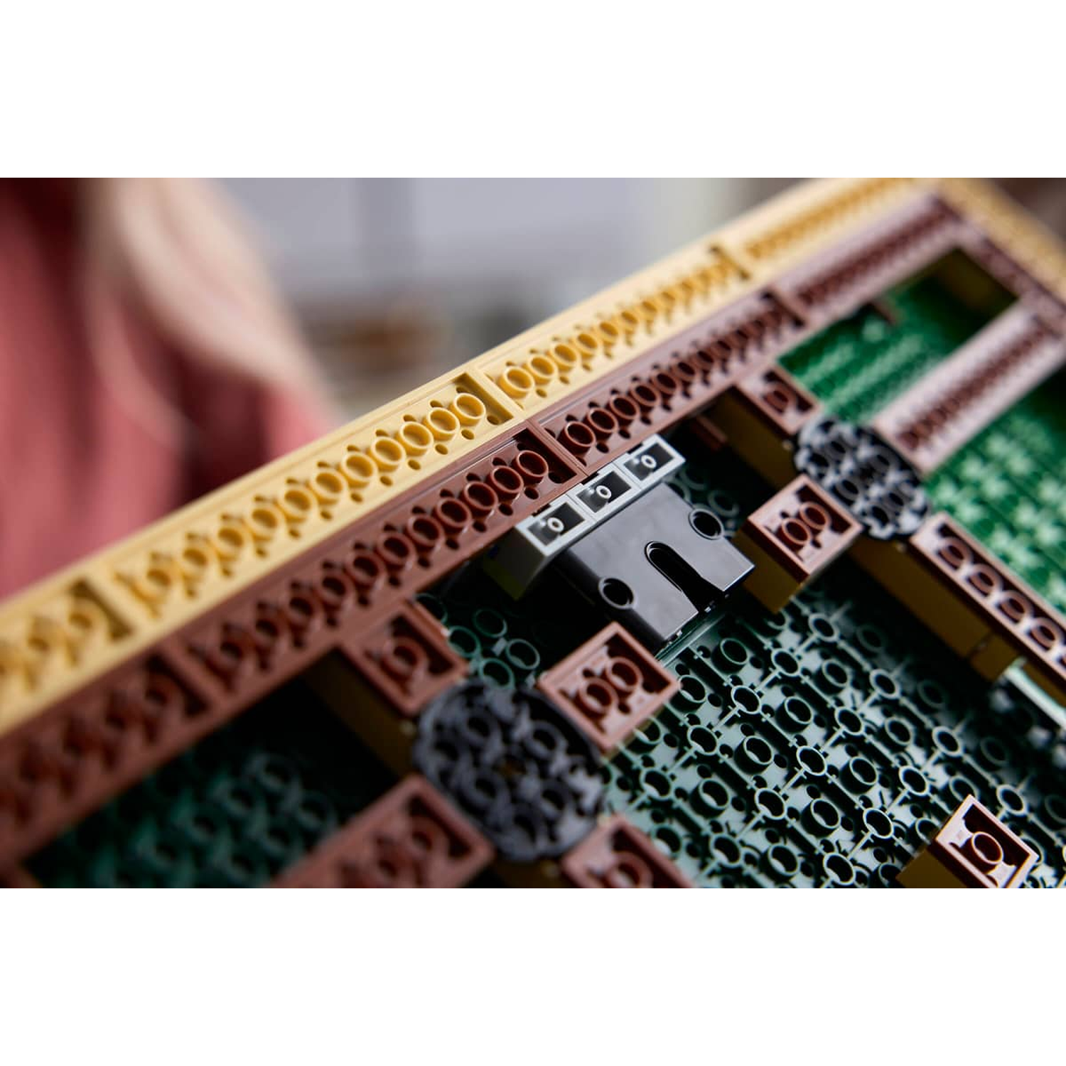 Close-up of tan, brown, and green Lego bricks with a black connector piece.