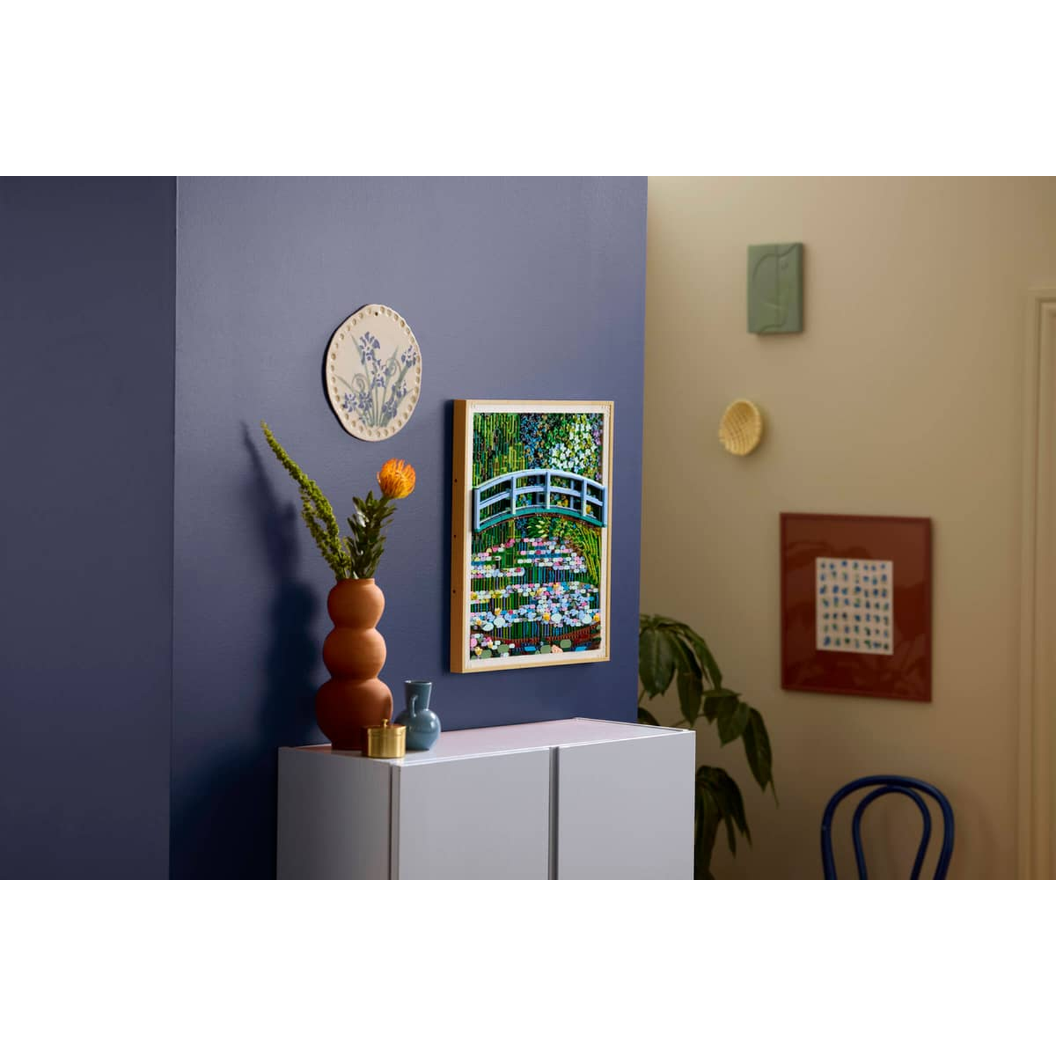 A Lego rendition of Monet's bridge over a pond with flowers, displayed on a cabinet.