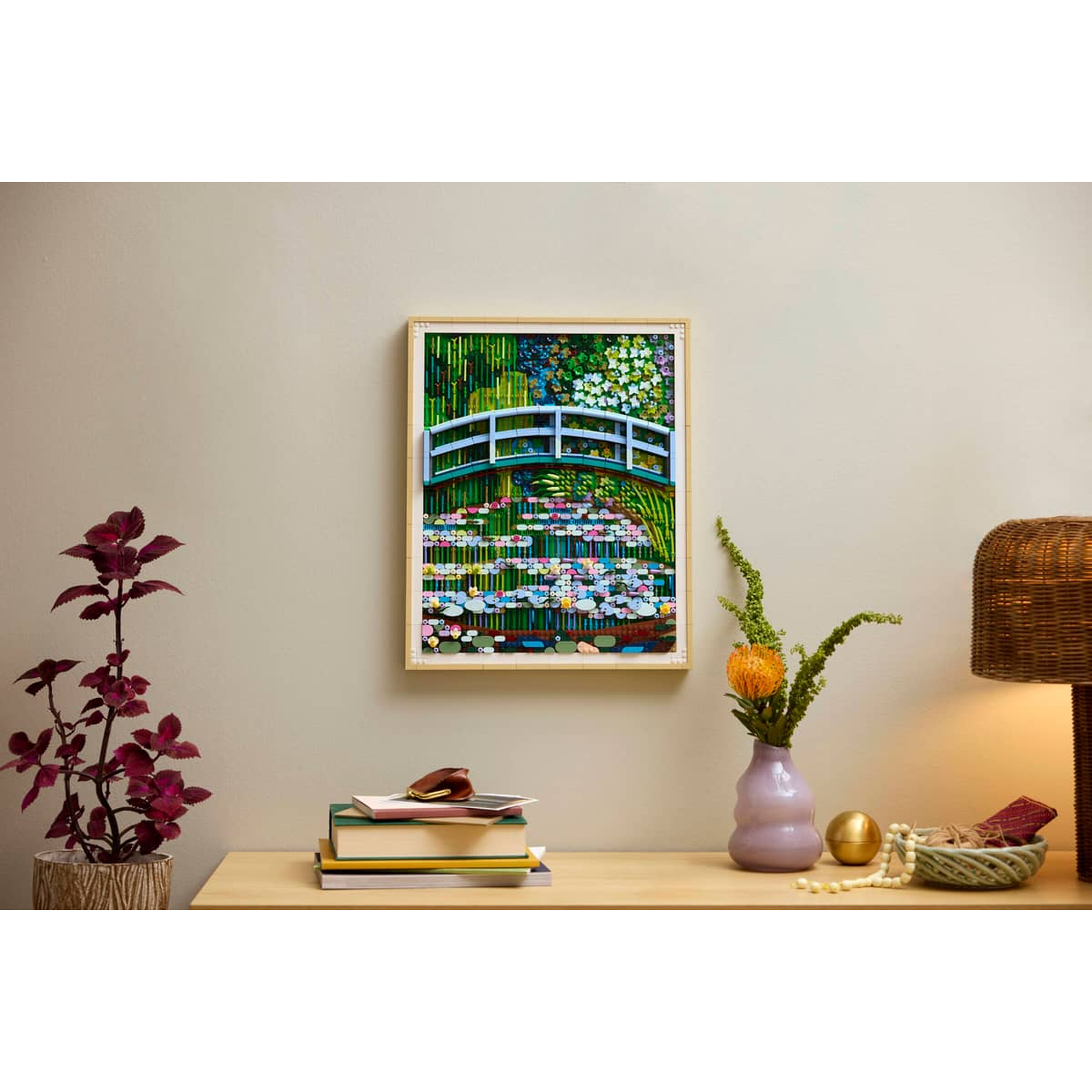 A framed picture of a Japanese bridge over water lilies with flowers and plants.