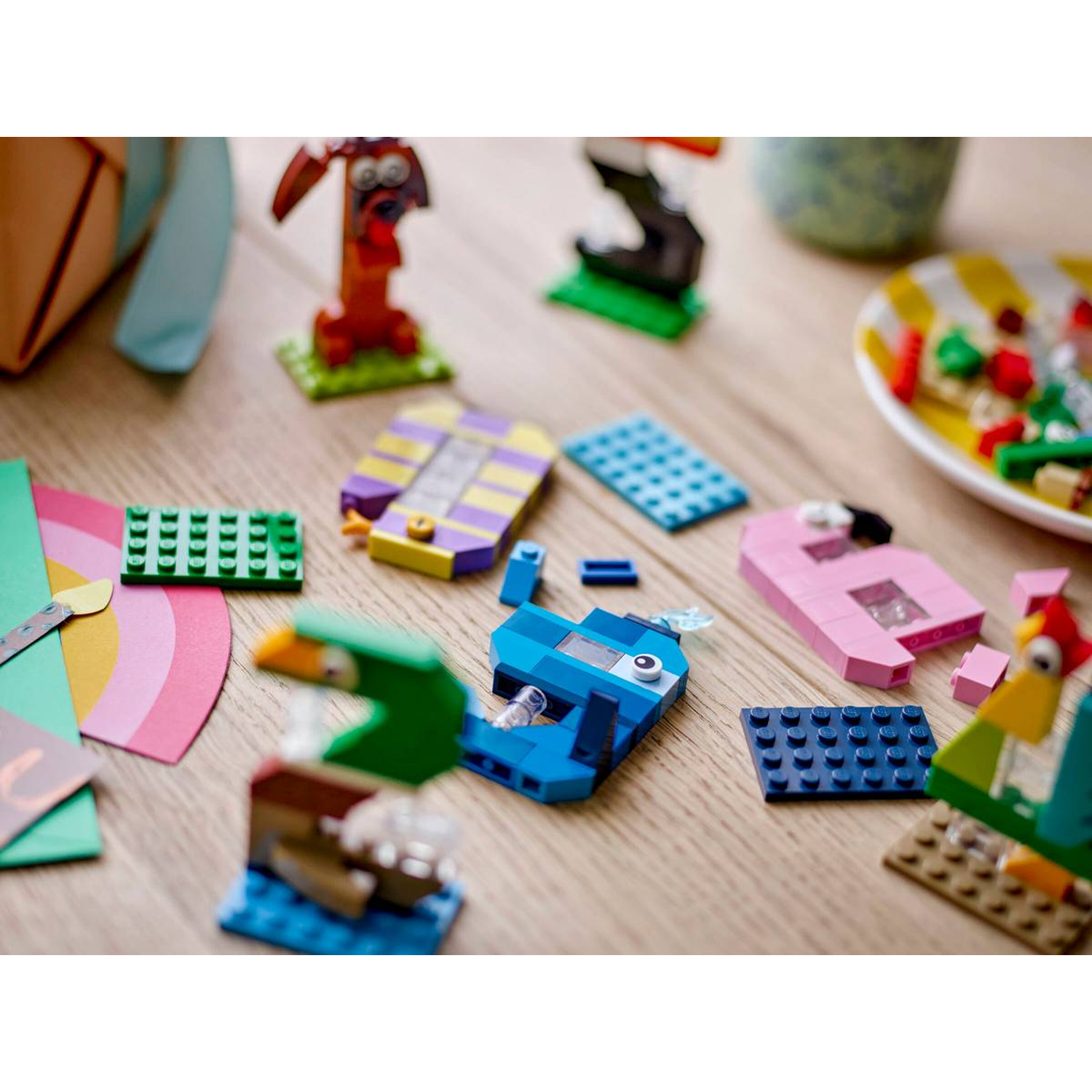 Kleurrijke LEGO-figuren en blokken op houten tafel. Hond, eend, walvis en haan.