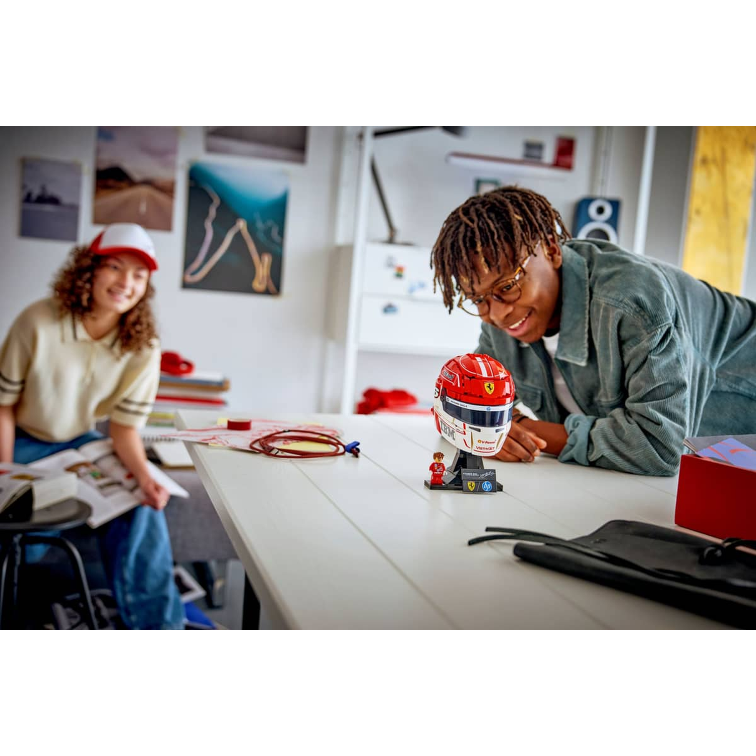 Twee mensen bekijken een rood Ferrari-helmmodel op een tafel.