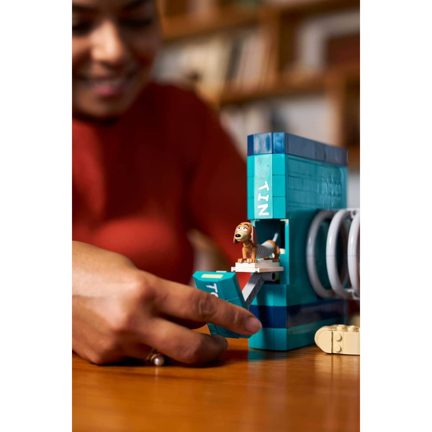 Een hondenspeeltje op een blauwe Lego-structuur, bediend door een vrouw.