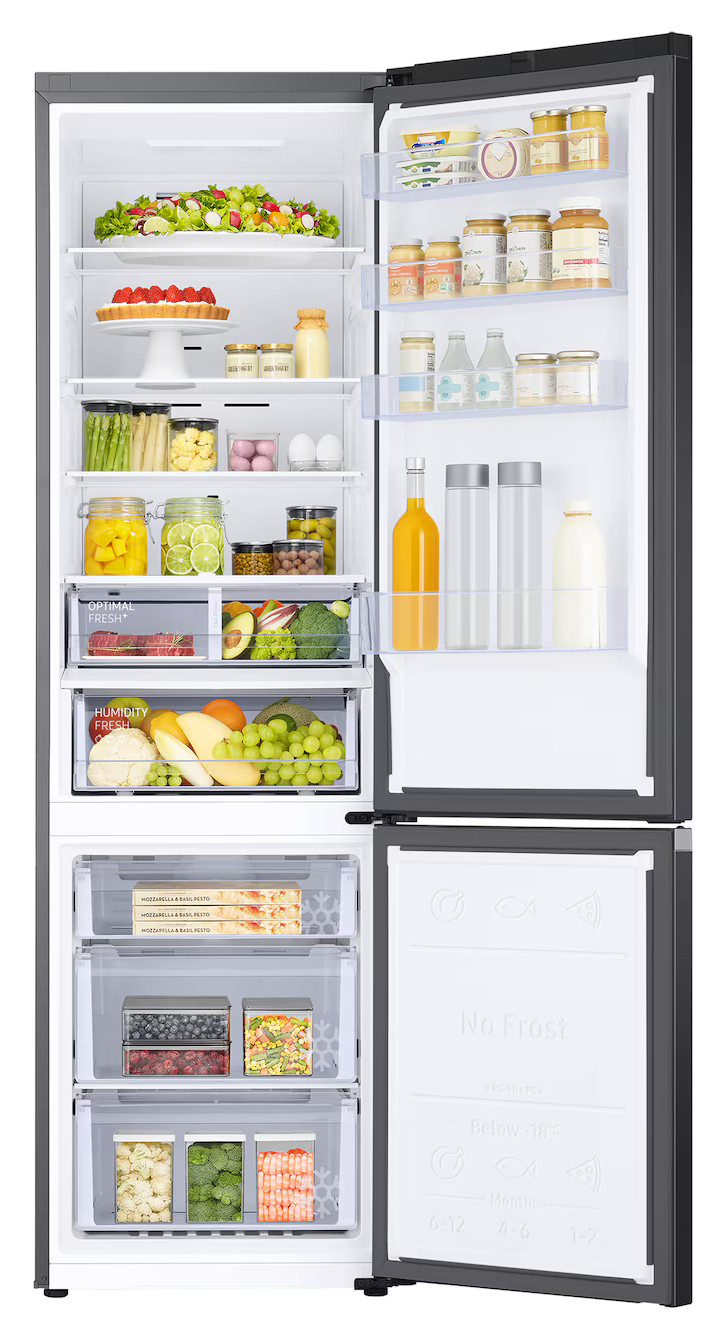 Otwarta lodówka wypełniona jedzeniem, w tym owocami, warzywami, serem i napojami.
