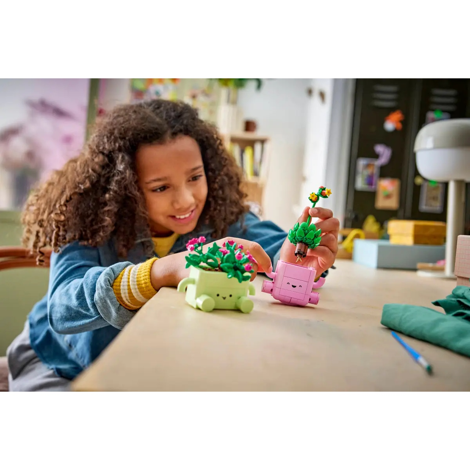 A girl builds a small green and pink planter with colorful LEGO bricks.