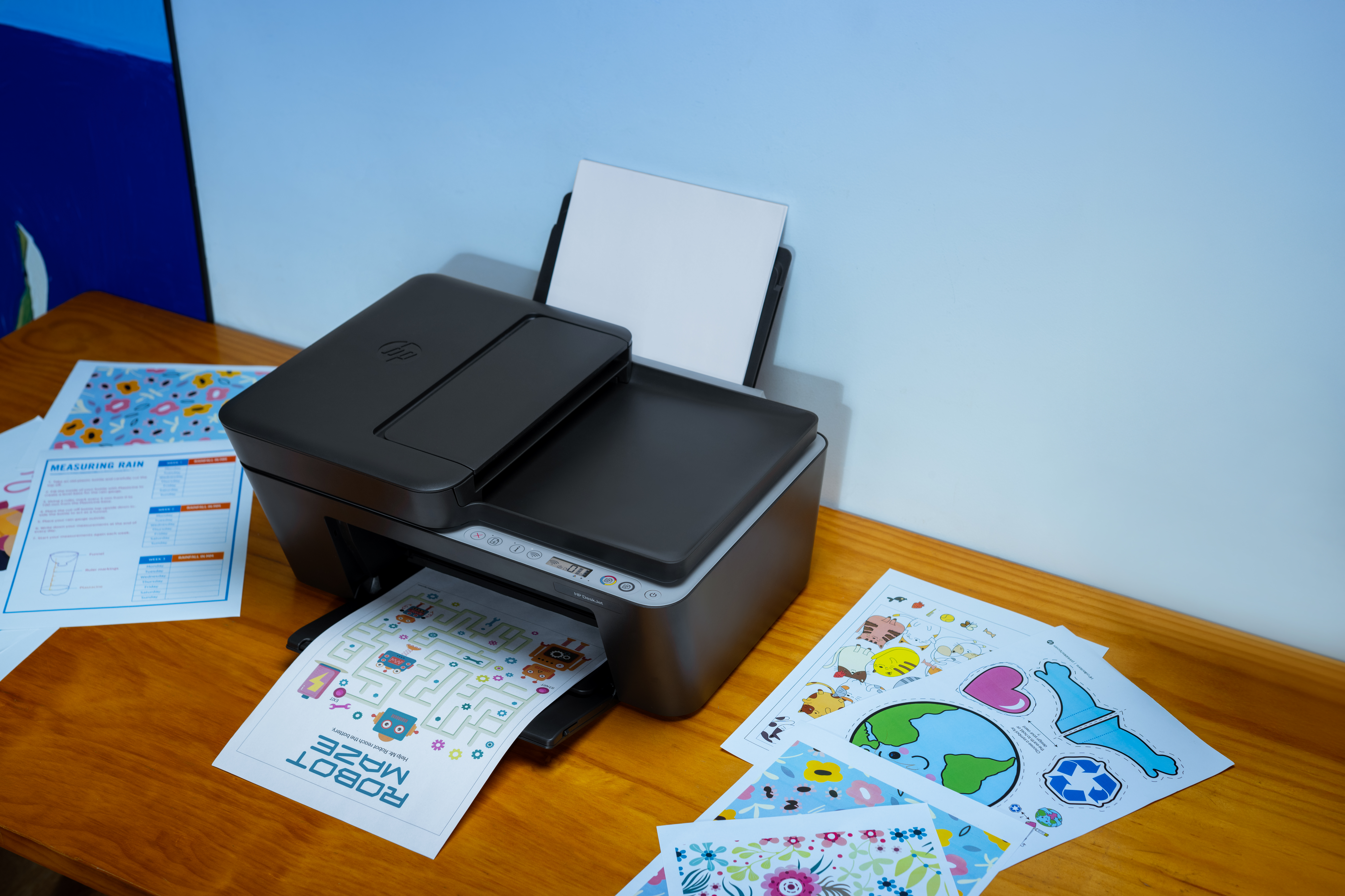 Ein Drucker druckt eine Labyrinth-Spielseite mit Robotern und Aufklebern.