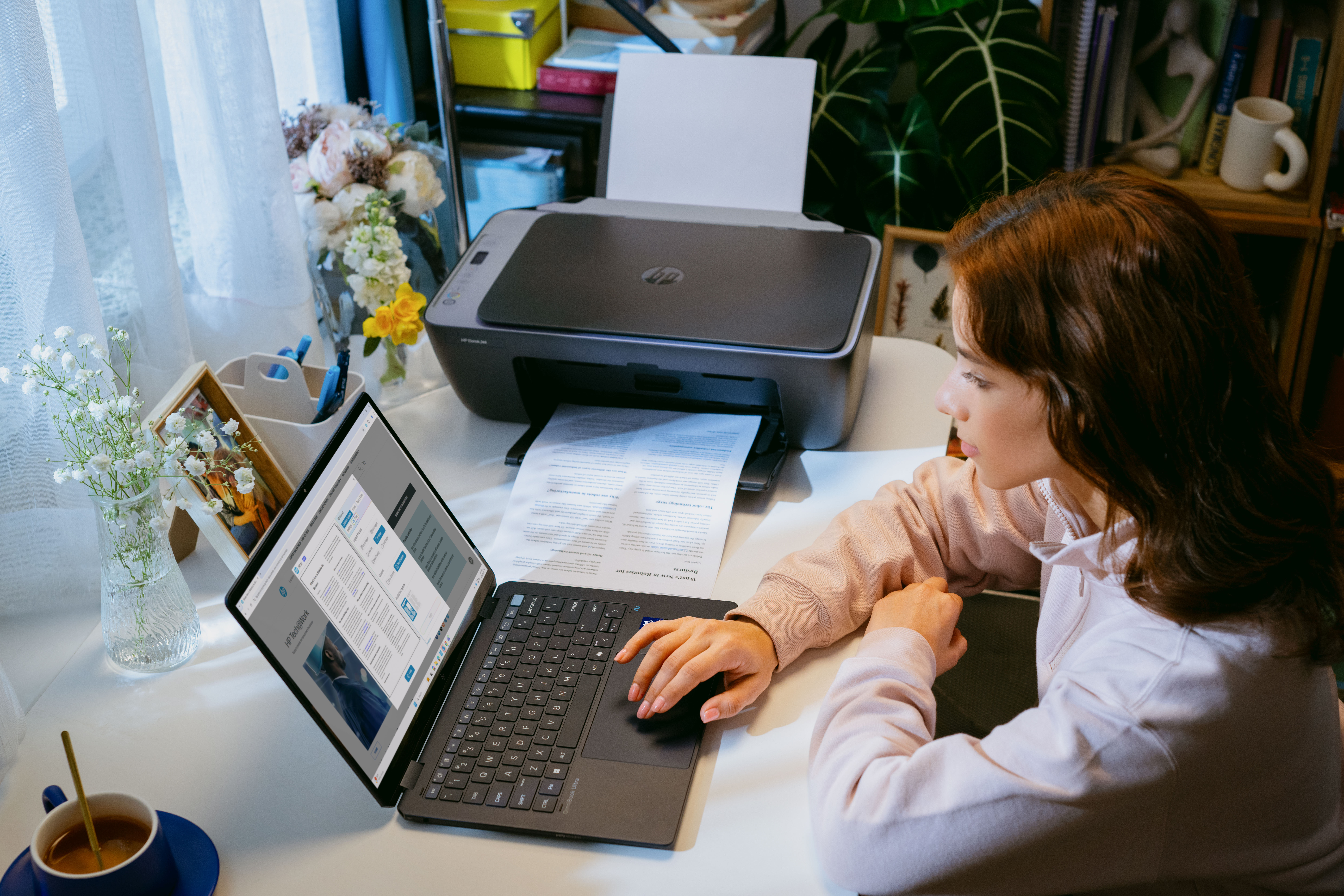 Eine Frau arbeitet an einem Laptop, während ein Drucker Papier ausgibt.